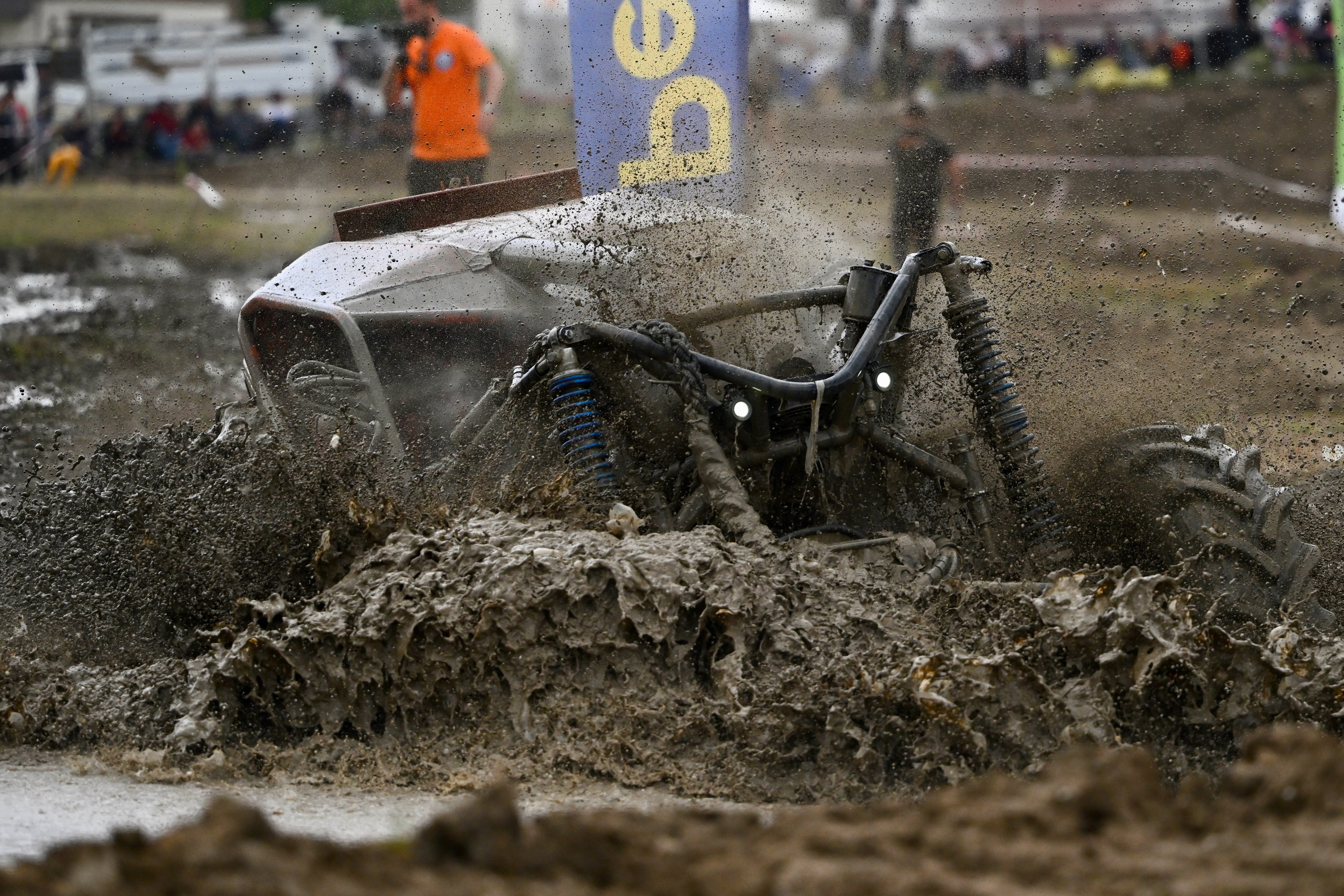 An off-road vehicle is driven through a very deep and muddy section of a race course.