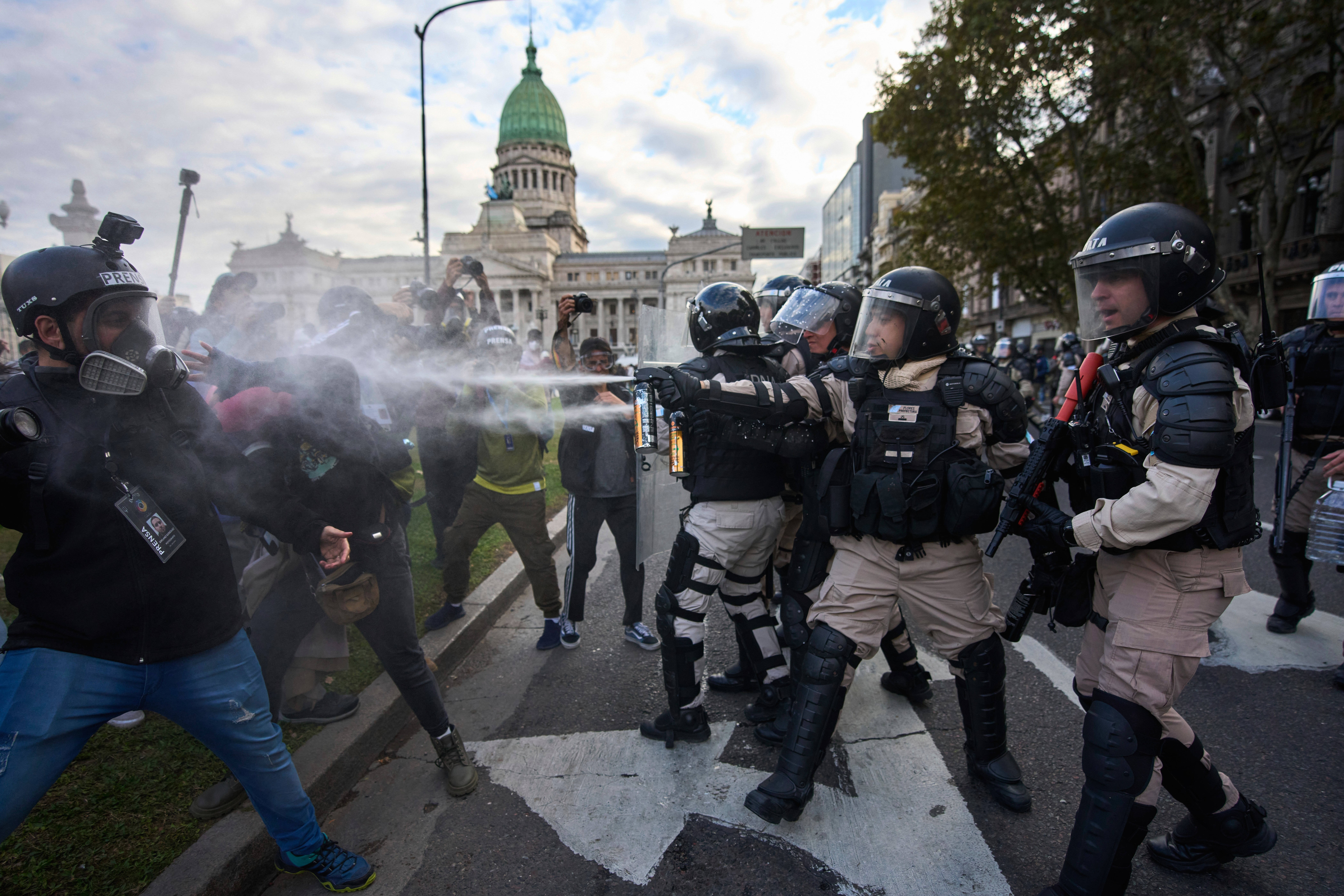 Riot police officers spray tear gas at protestors.