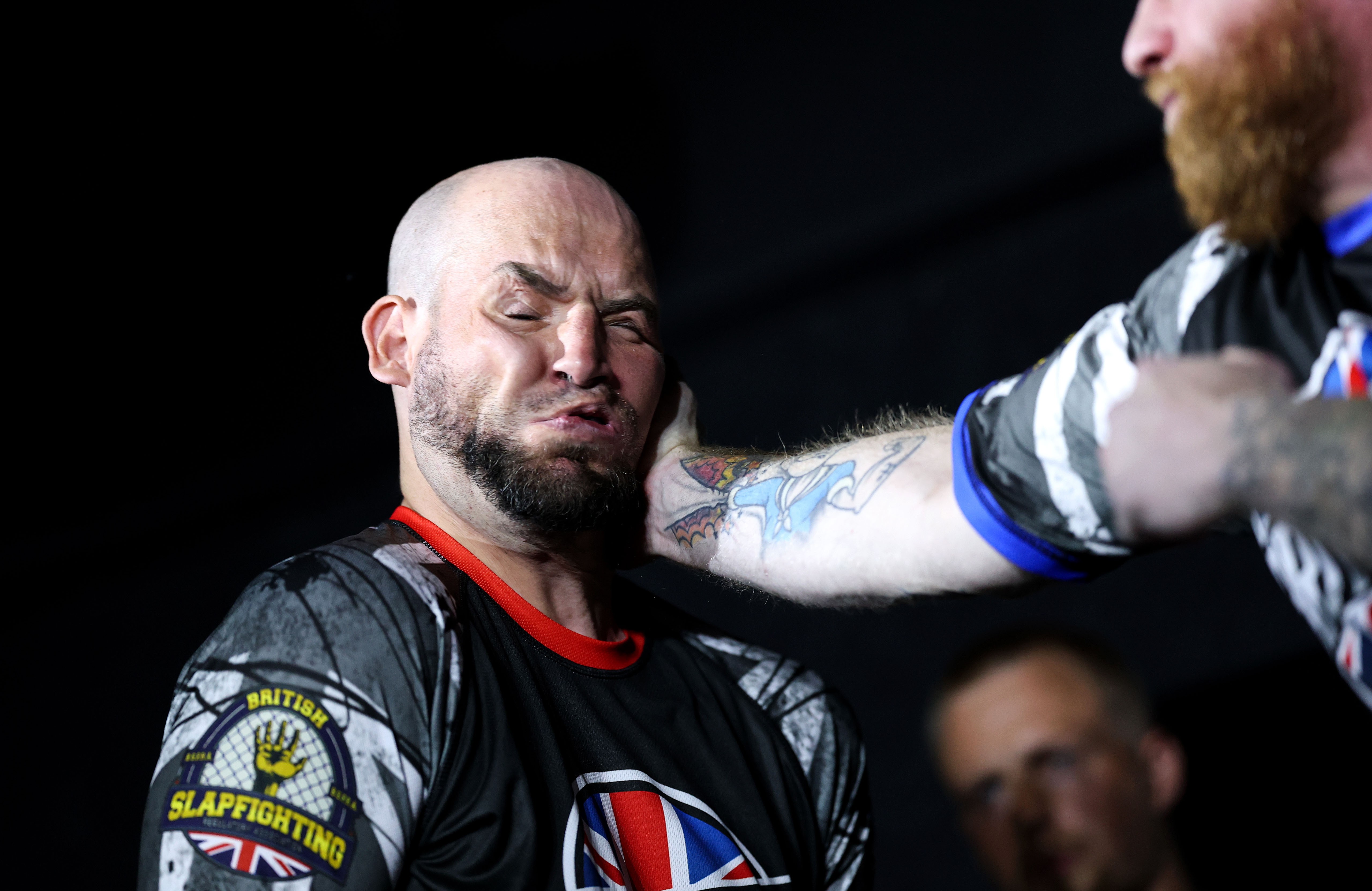 One man is slapped hard in the face by another man during a slap fight match.