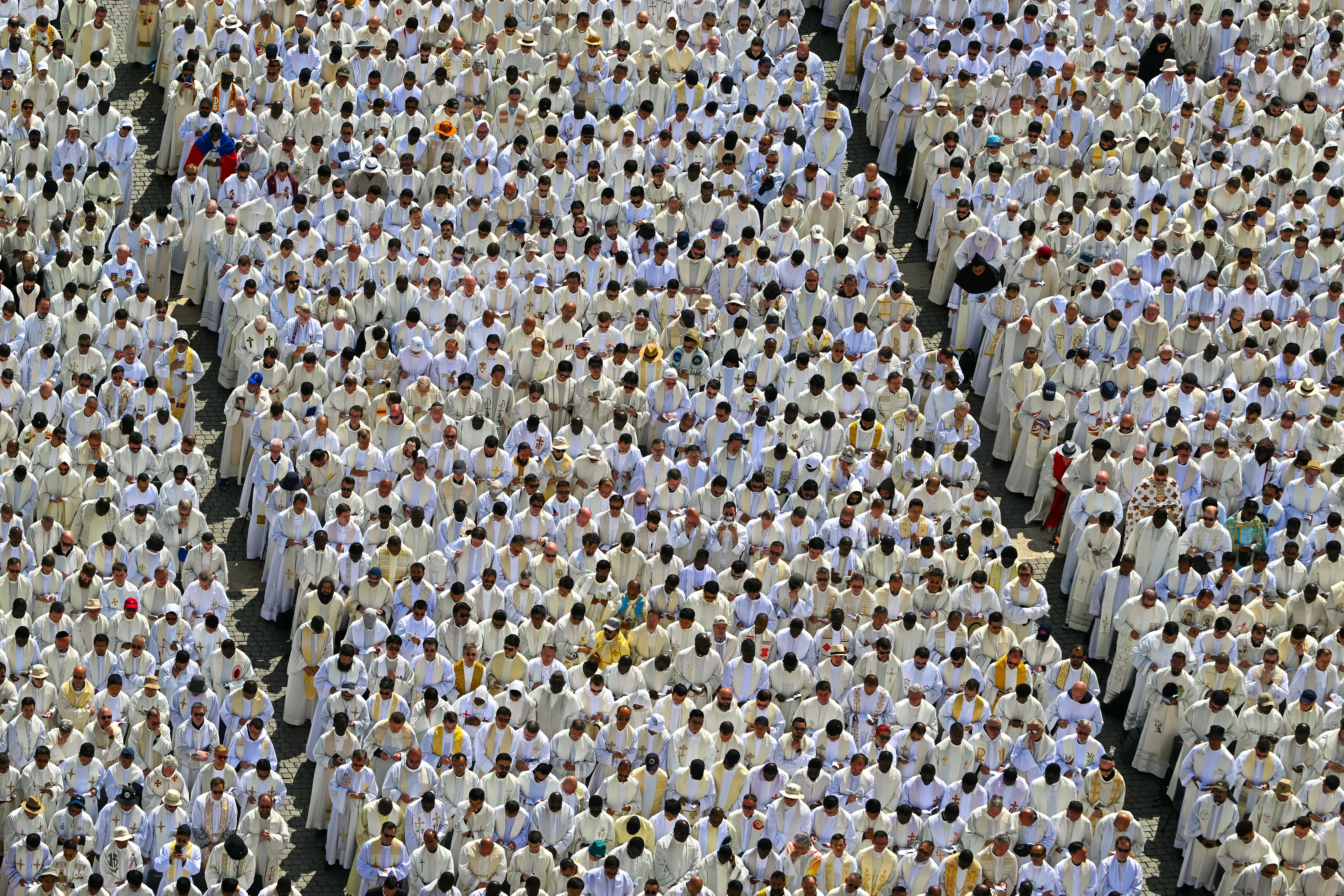 Many rows of priests stand during a ceremony at the Vatican.