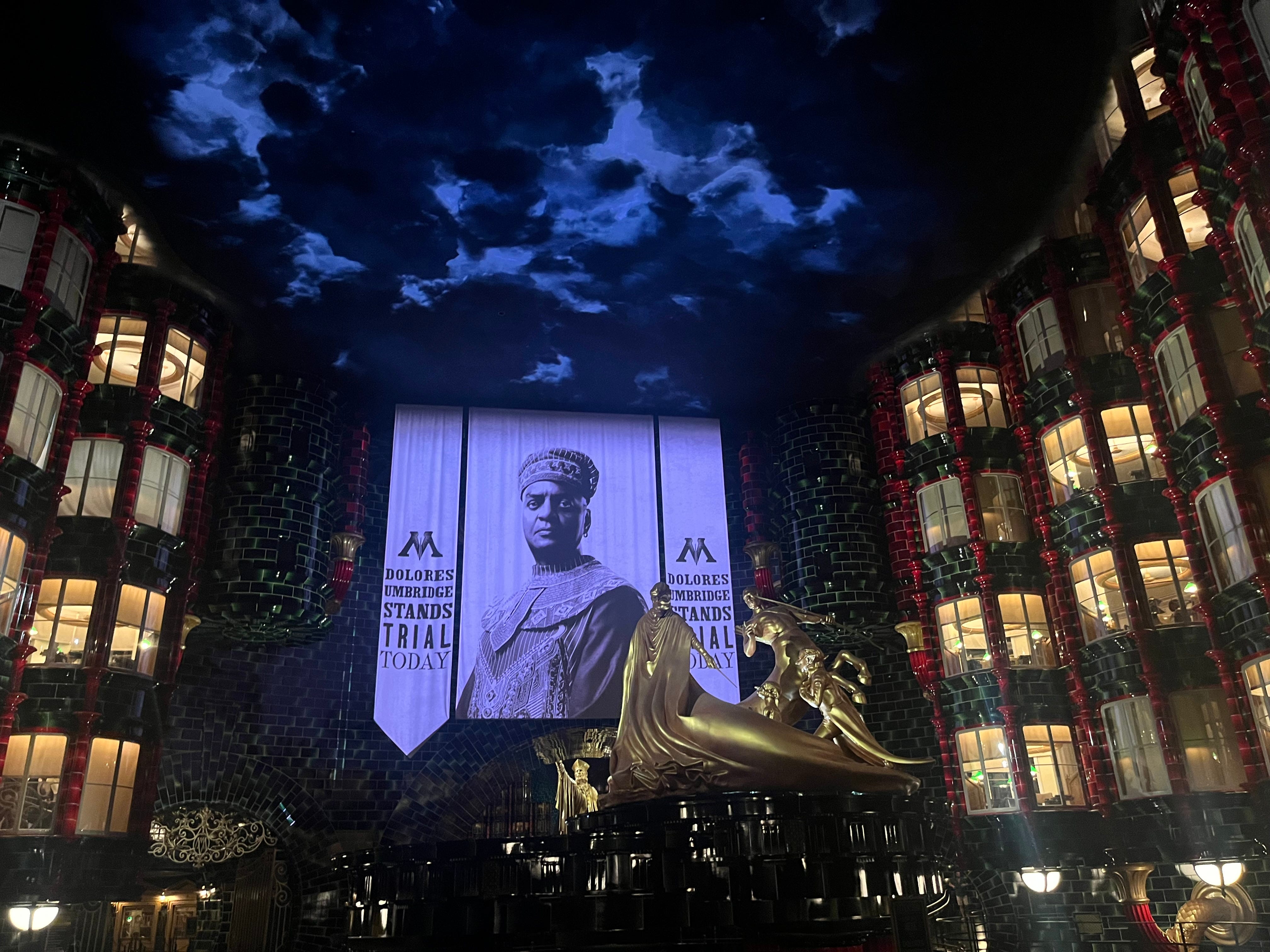 Themed queue area with large wizard posters, lights, and fake sky in the wueue for Battle at the Ministry at Epic Universe
