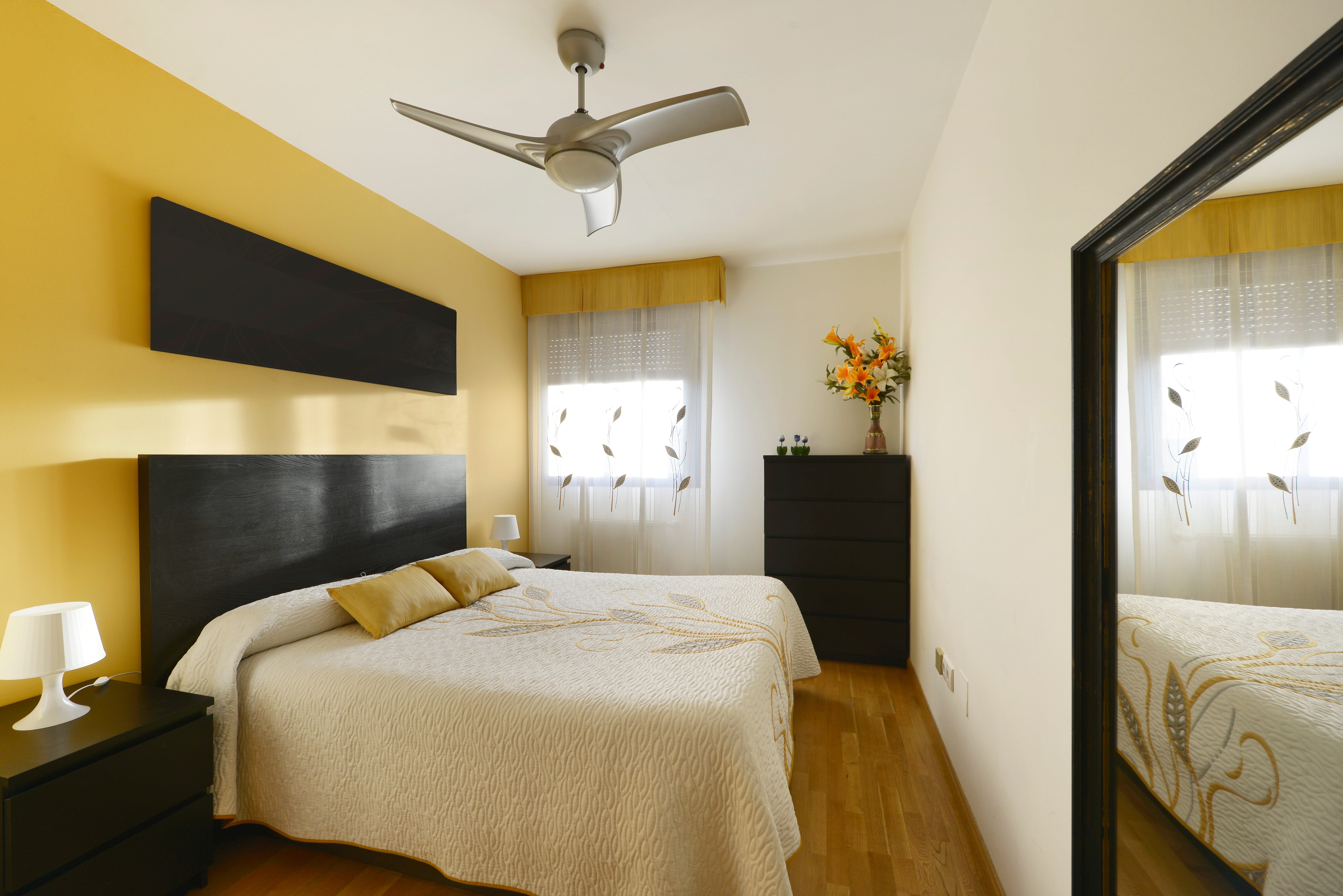 A small yellow bedroom with matching black furniture.