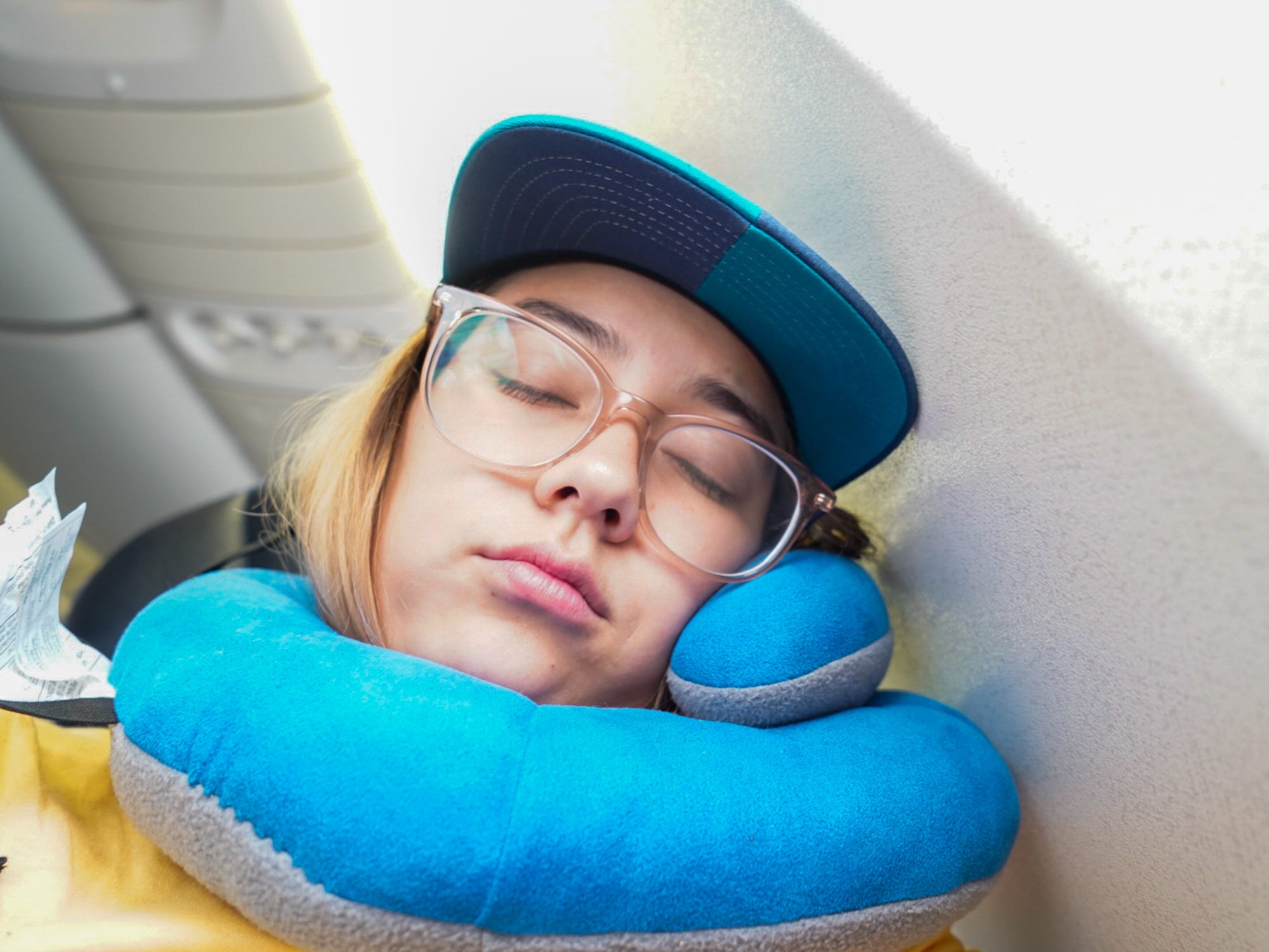 The author rests with a neck pillow on an airplane