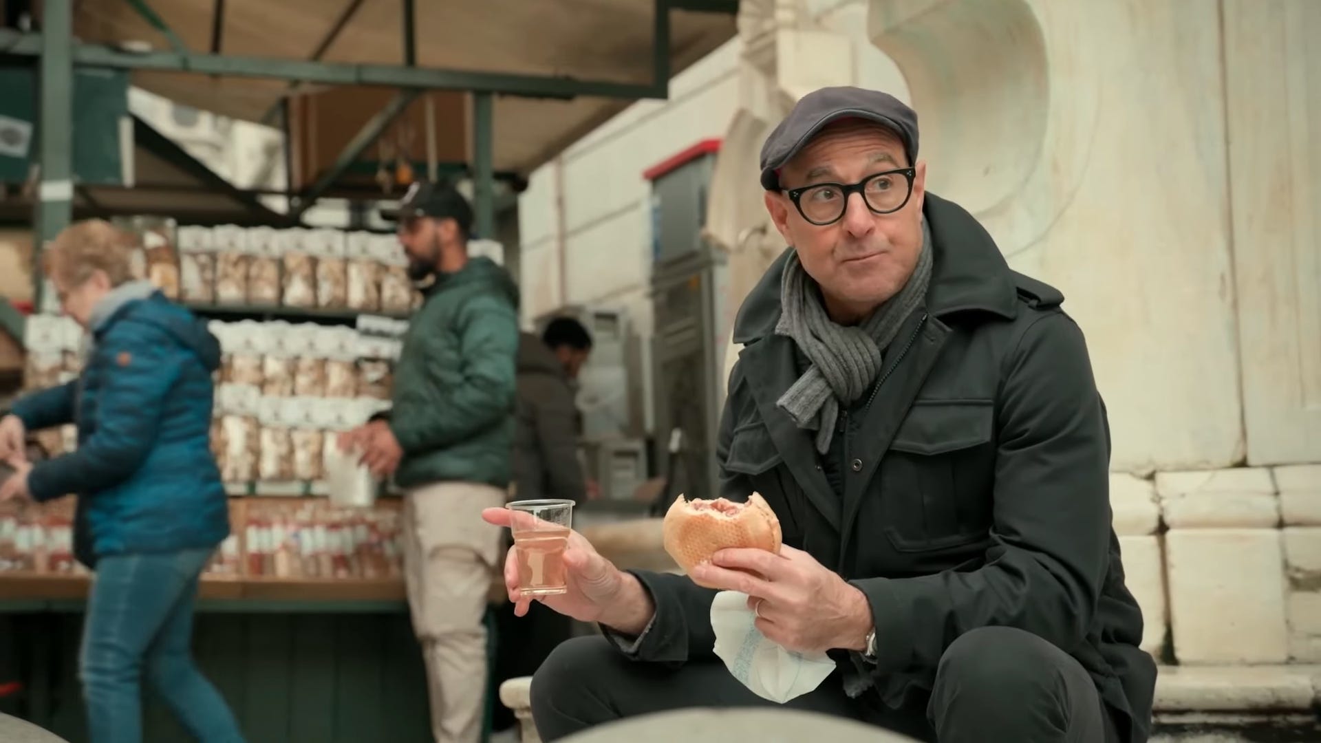 A man holding a drink in one hand and a sandwich in the other.