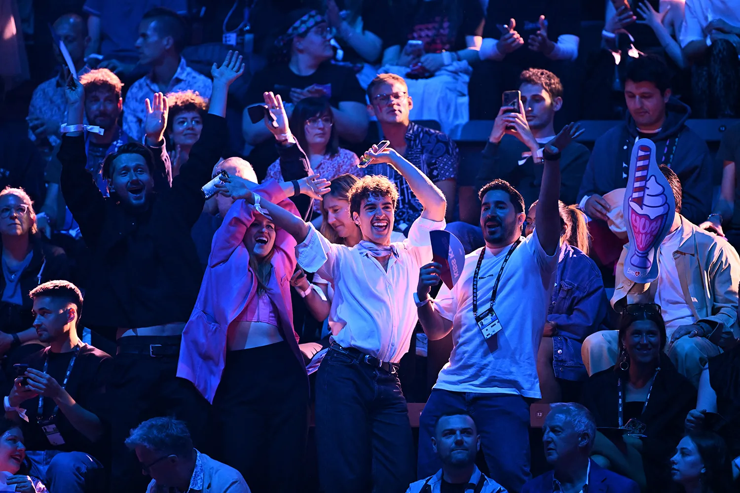 A person waves their hands and dances at teh center of a standing crowd.