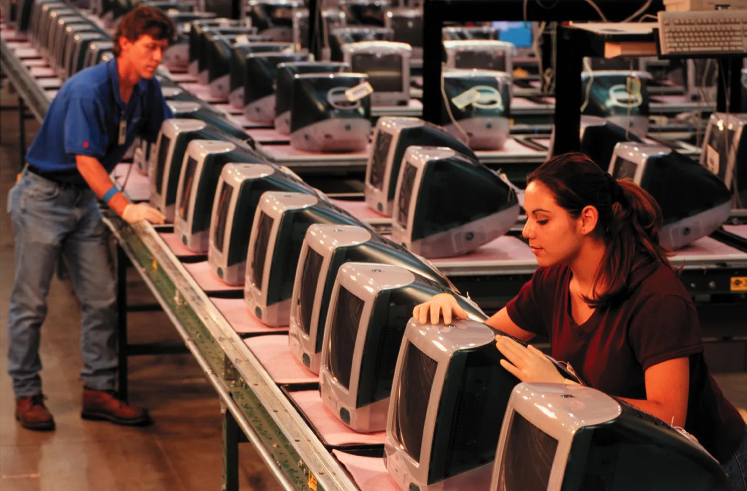 Rows of vintage iMac computers with a worker behind one of them.