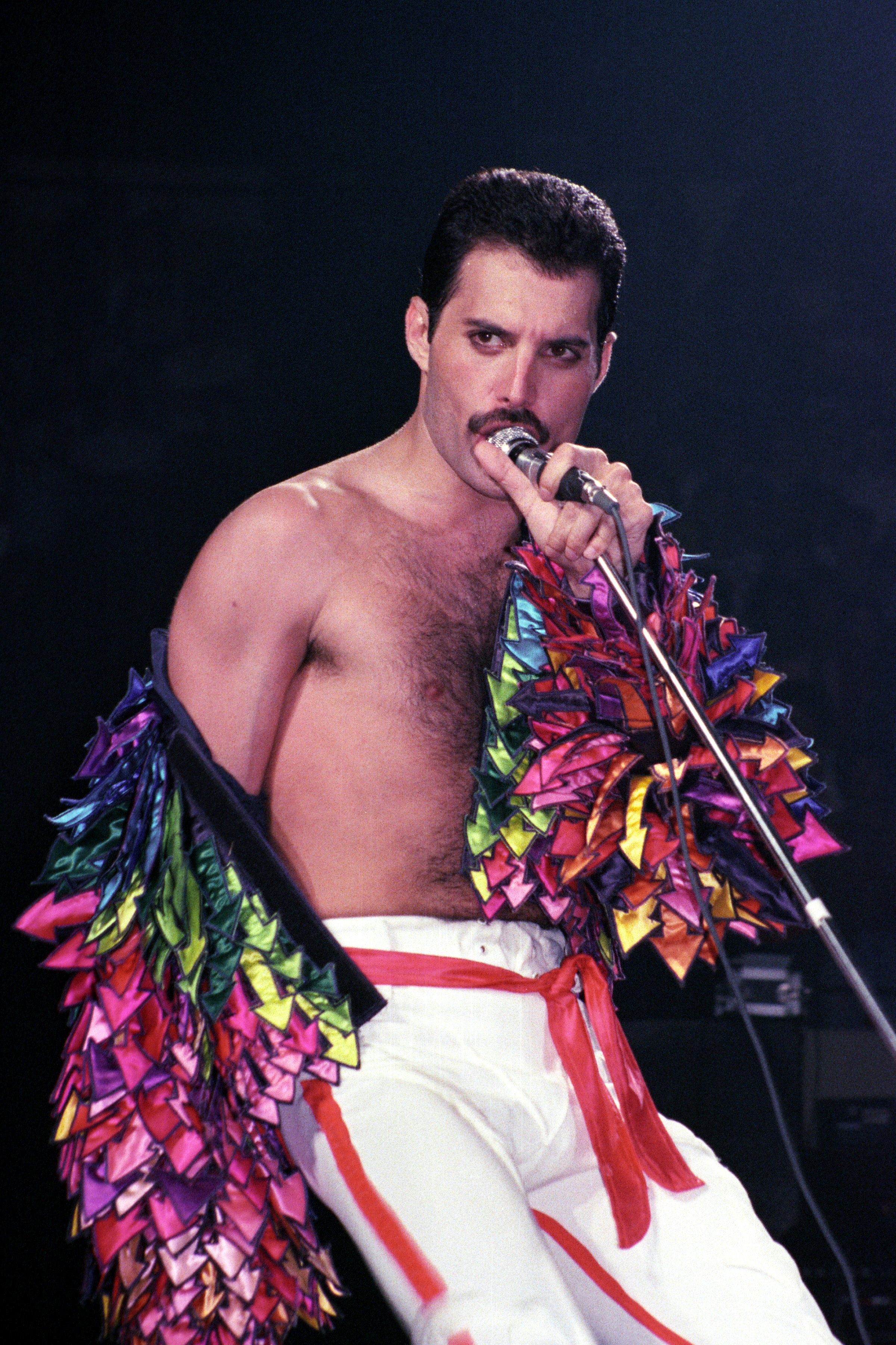 Freddie Mercury in a colorful coat onstage. 