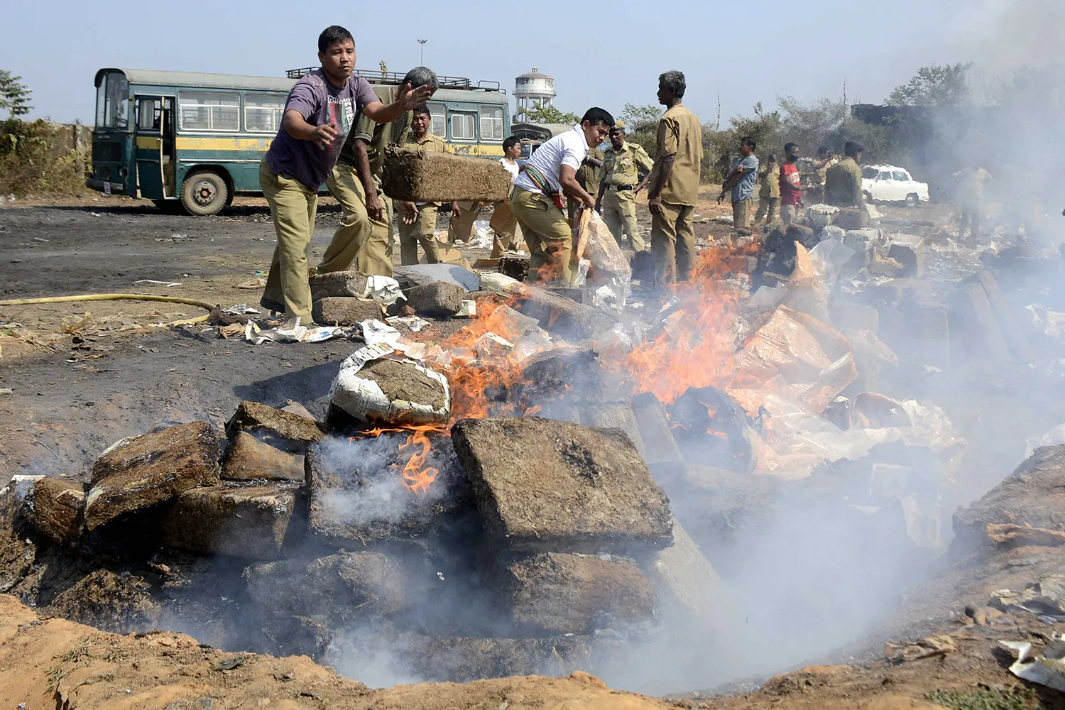 Indian police throw blocks of confiscated marijuana onto a bonfire