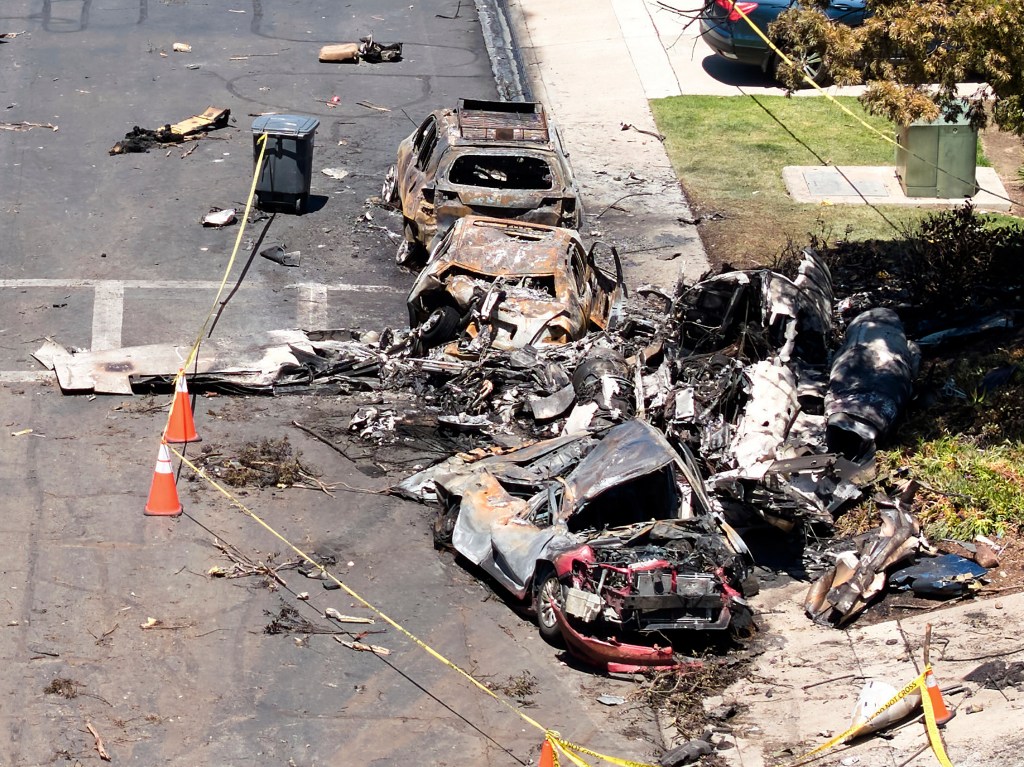 Debris covers the ground after a small plane crashed into a San Diego neighborhood, setting homes and cars on fire and forcing evacuation.