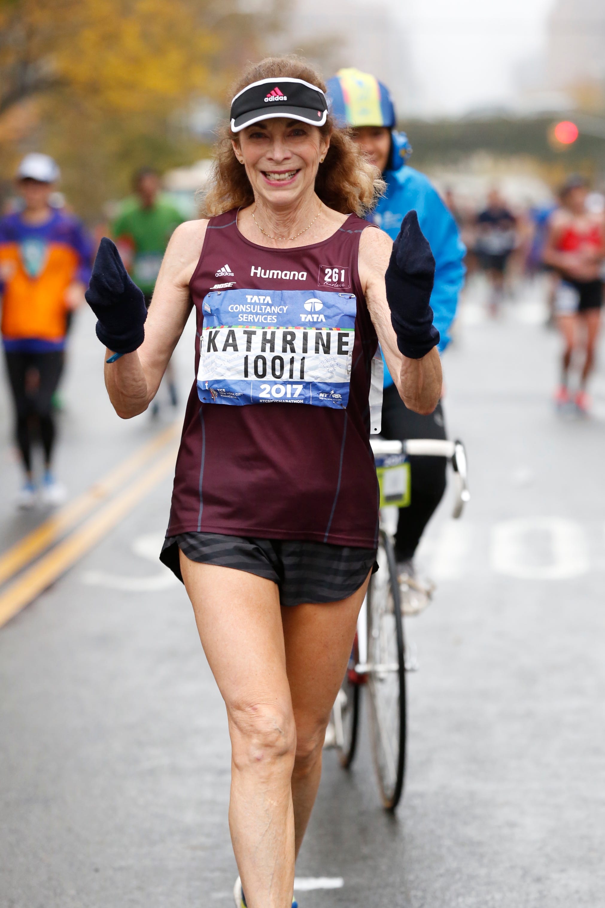 A woman, wearing a vest that reads, "Kathrine," running.