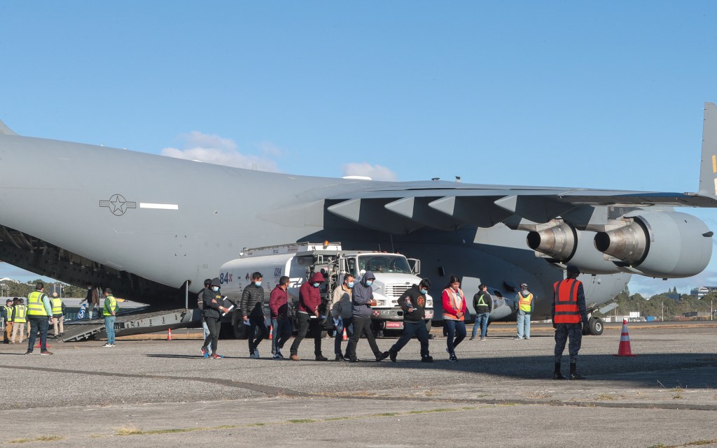 Deported migrants walk off a US military plane after arriving in Guatemala City on Jan. 24, 2025.