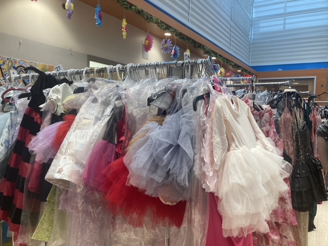 Patients and staff choosing from racks of donated clothing in a repurposed recreation room, now a designer atelier with available makeup artists