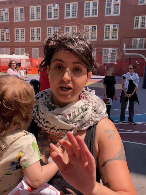 cindy gorn holding a baby and appearing to usher someone holding the camera away from her