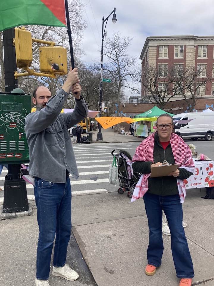 two protests including one holding a clipboard and another holding a flag