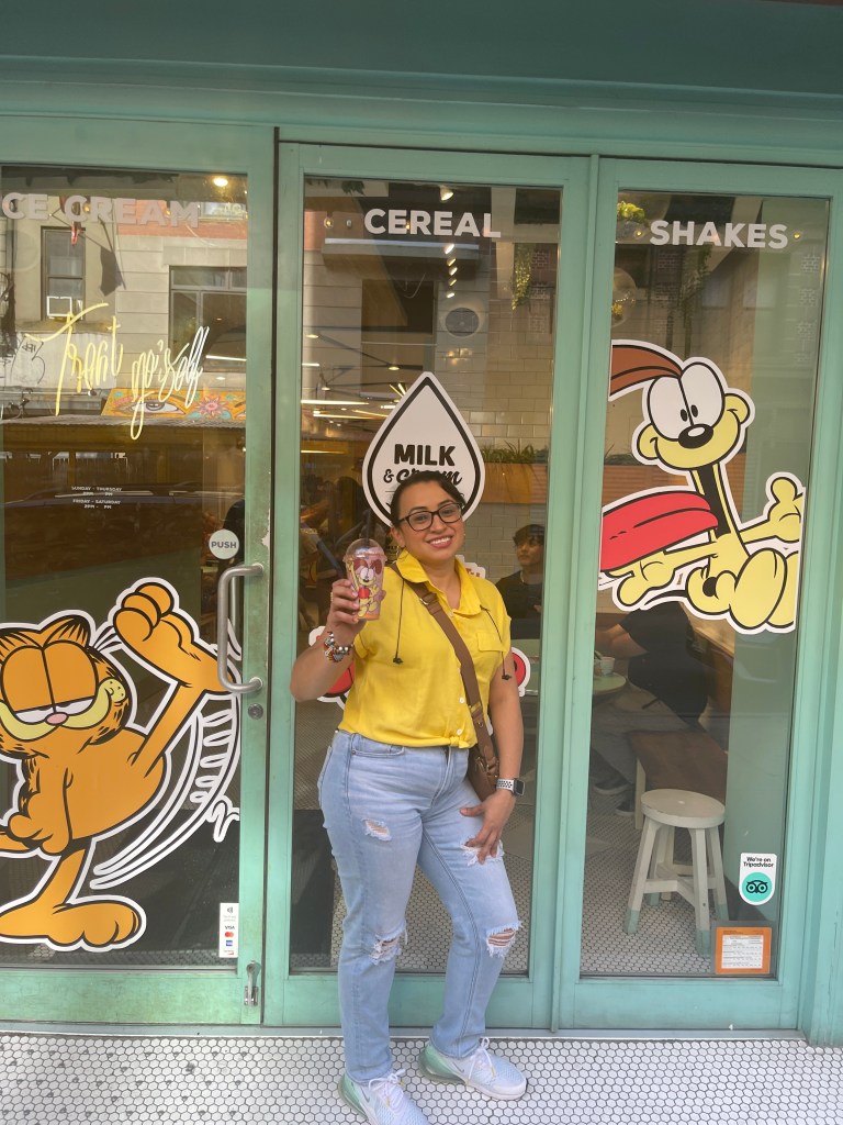 The mom outside an ice cream shop with a shake in her hand.