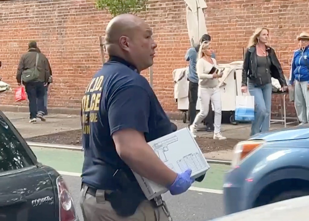 An NYPD investigator carries a gun box from the luxe address. 