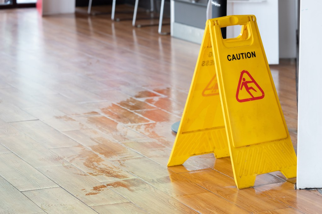 A stock photo of a slippery floor with a caution sign nearby.