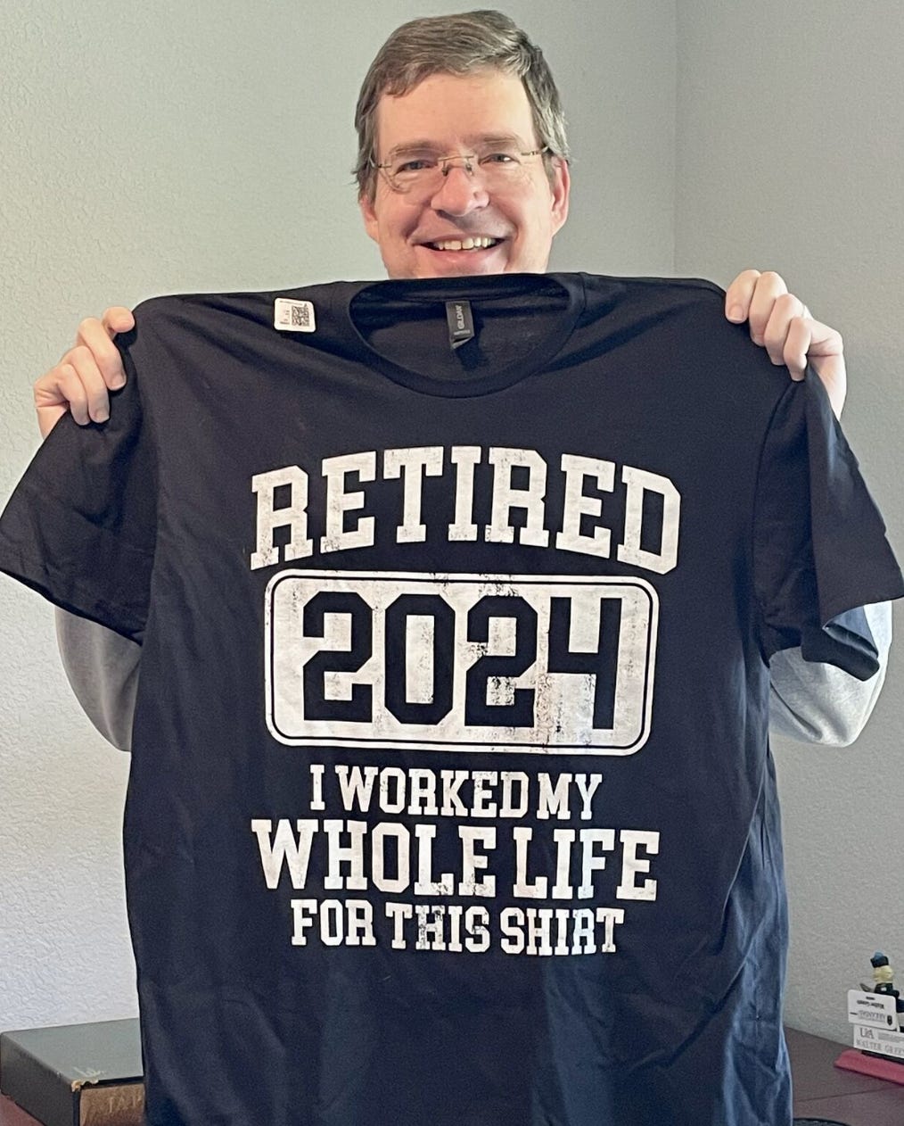 Walter Green holding up a "Retired 2024: I worked my whole life for this shirt" t-shirt.