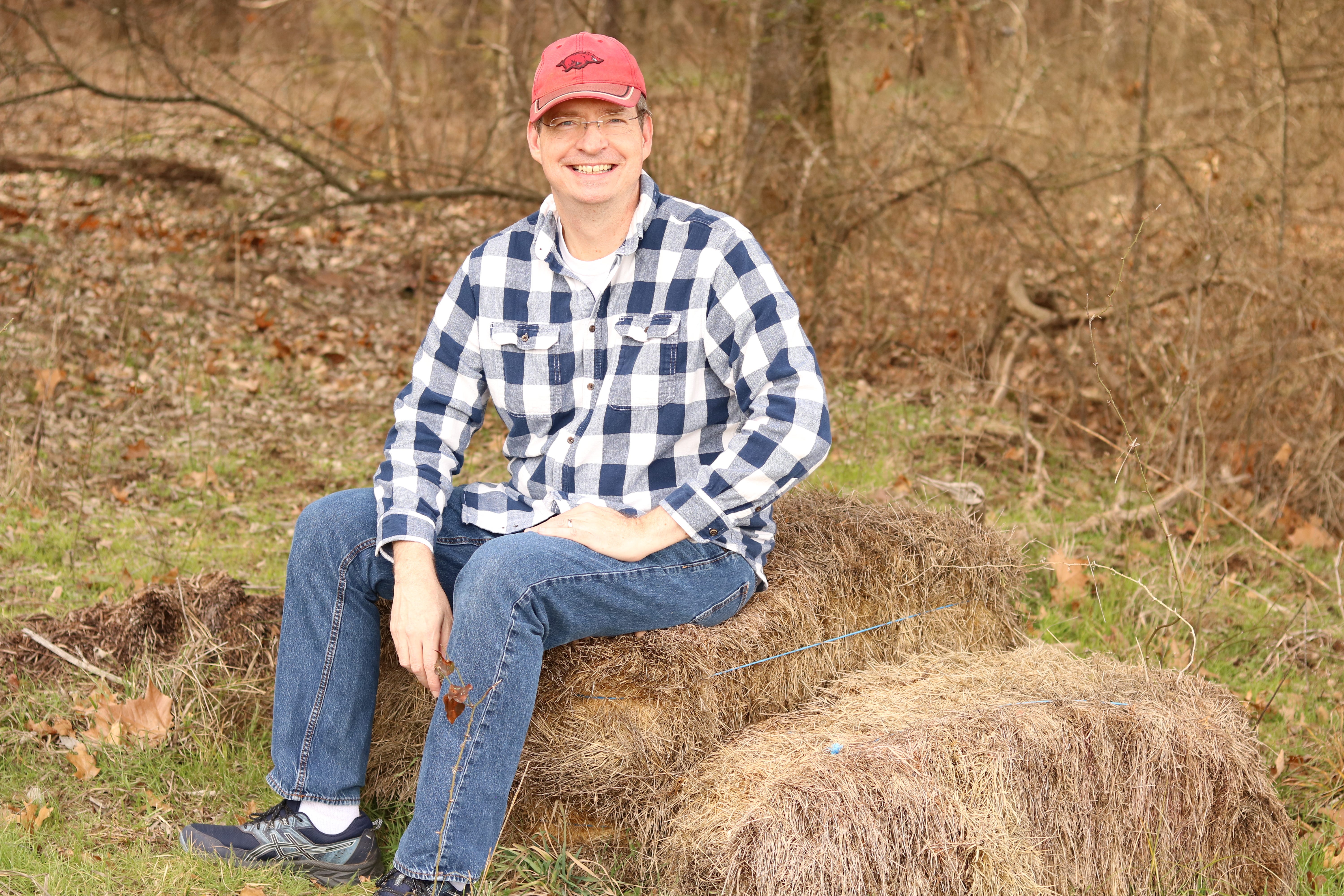 Walter Green sitting outdoors on a haystack.