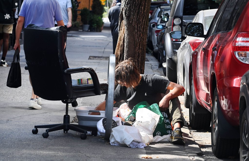 Homeless man sitting on the sidewalk on Greenwich Ave in the West Village, New York.