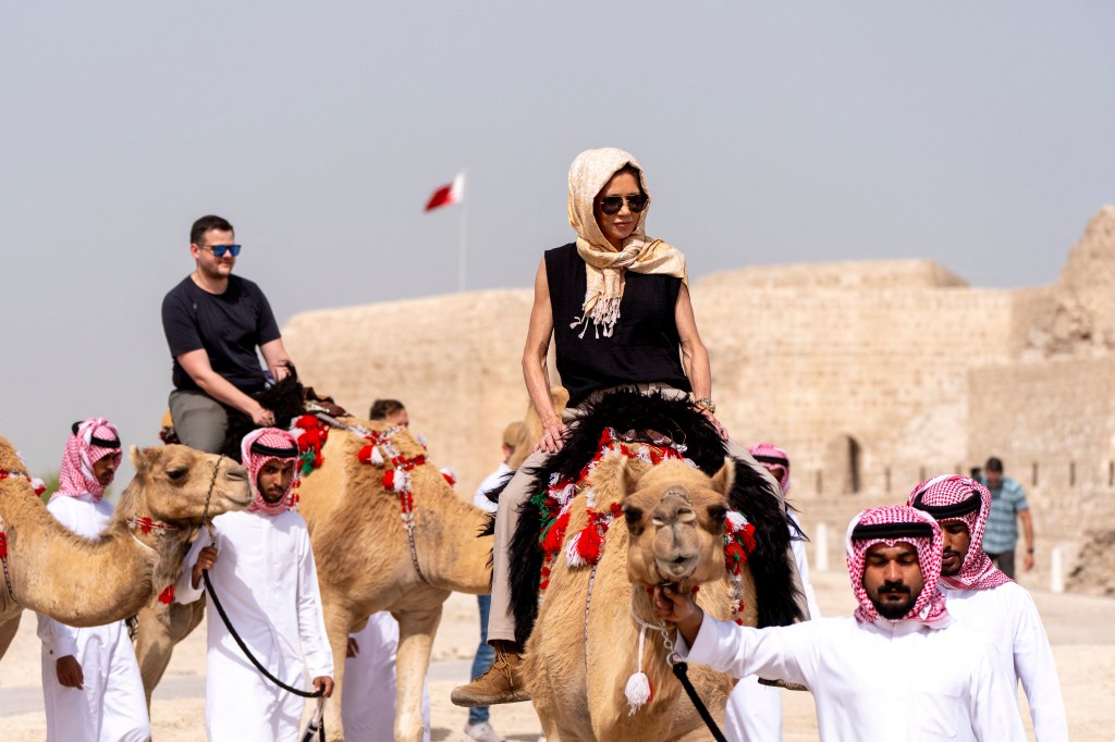 Noem (R) rides a camel after a tour of Qal'at al-Bahrain Fort near Manama on May 25, 2025.