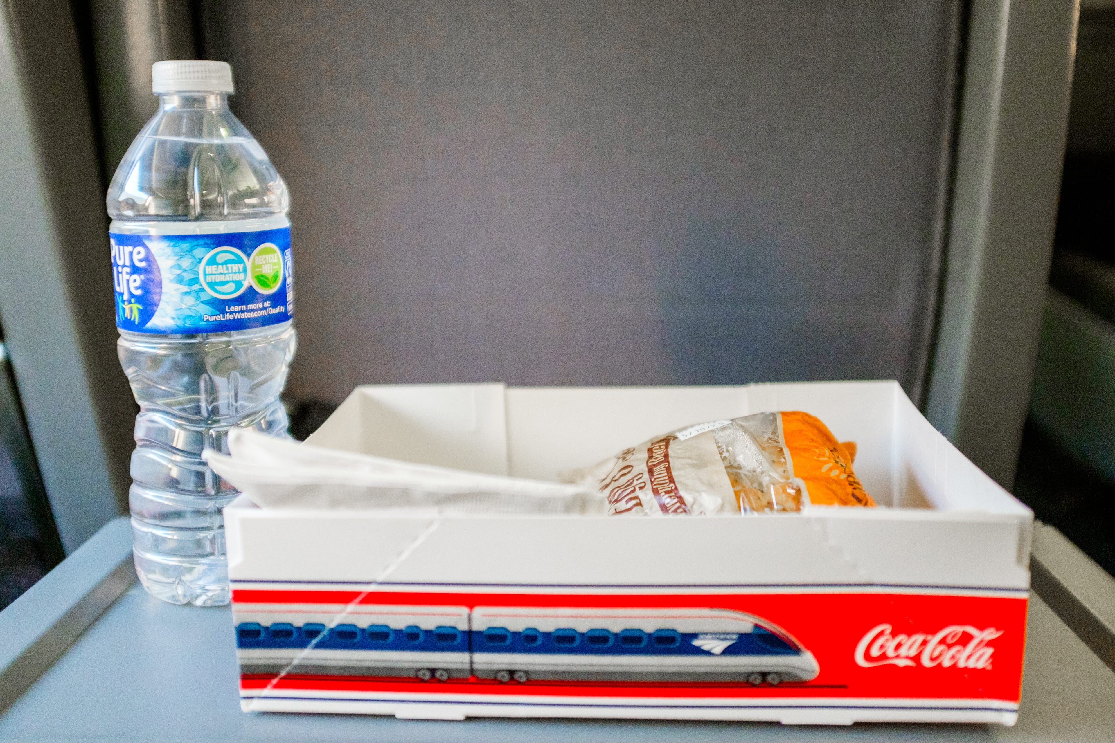 An Amtrak breakfast sandwich and a water bottle on a tray table