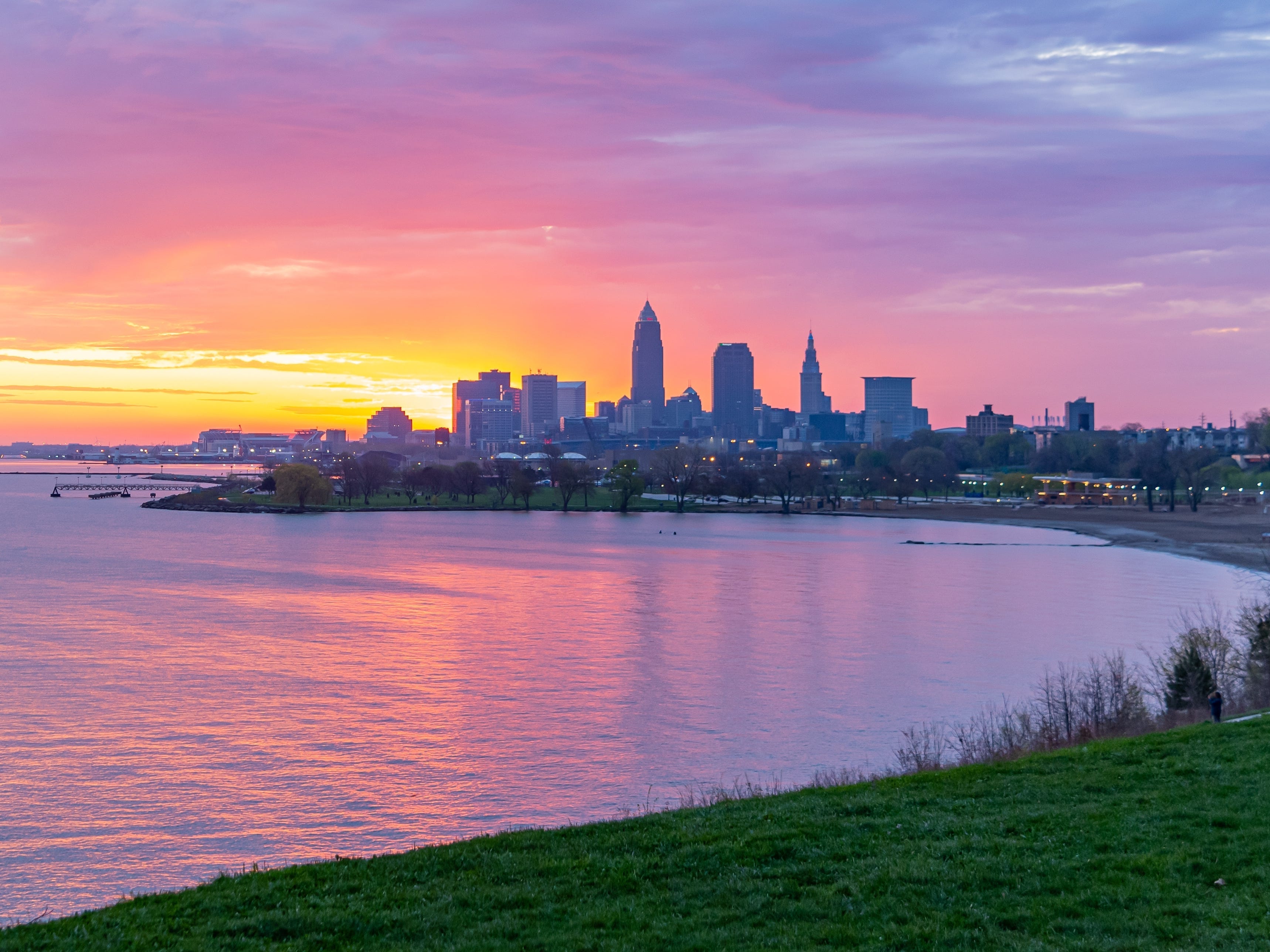 A pink-and-orange sunset behind tall buildings on a body of water