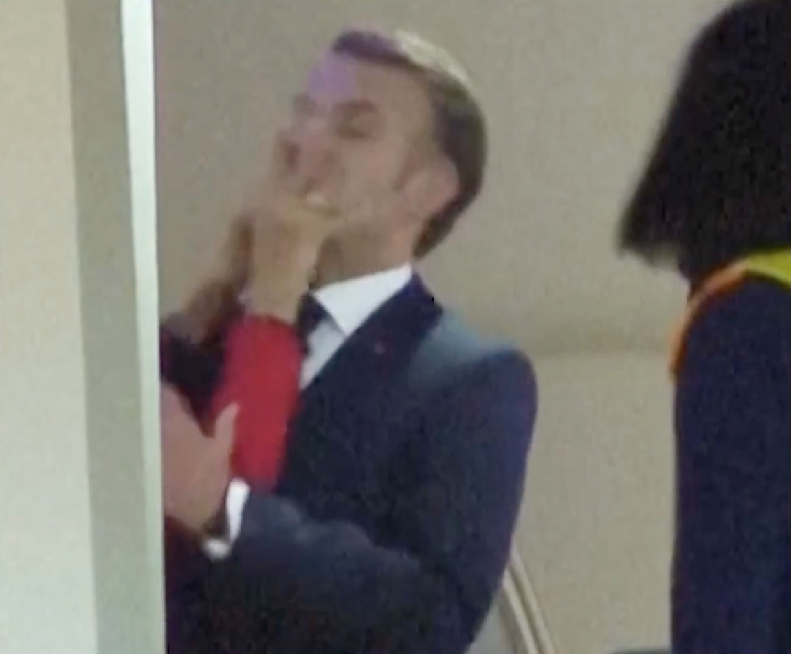 Brigitte Macron putting her hands on President Emmanuel Macron.