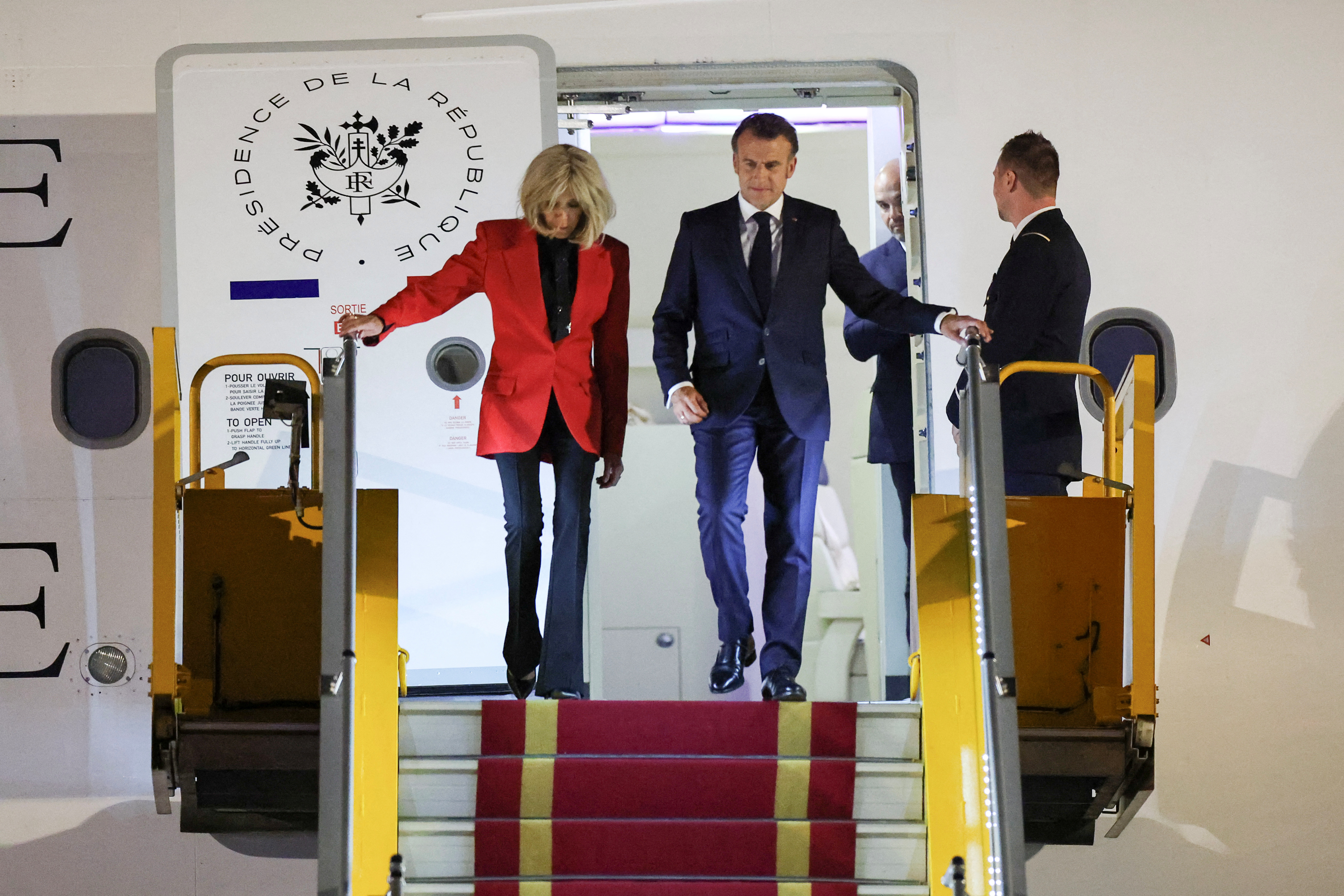 Brigitte Macron and President Macron walking down a plane.