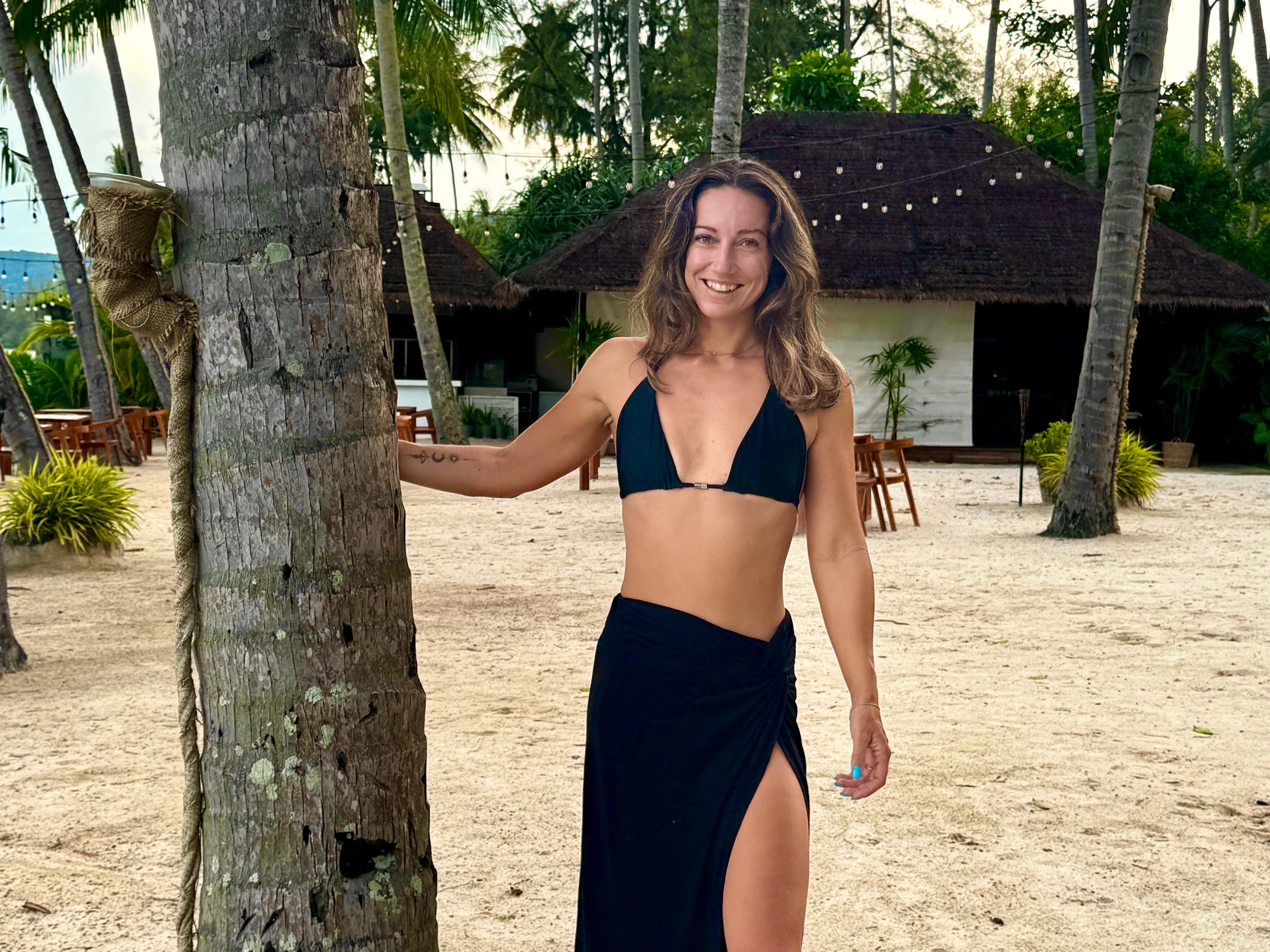 A woman posing with a tree on a beach in Koh Samui, Thailand.