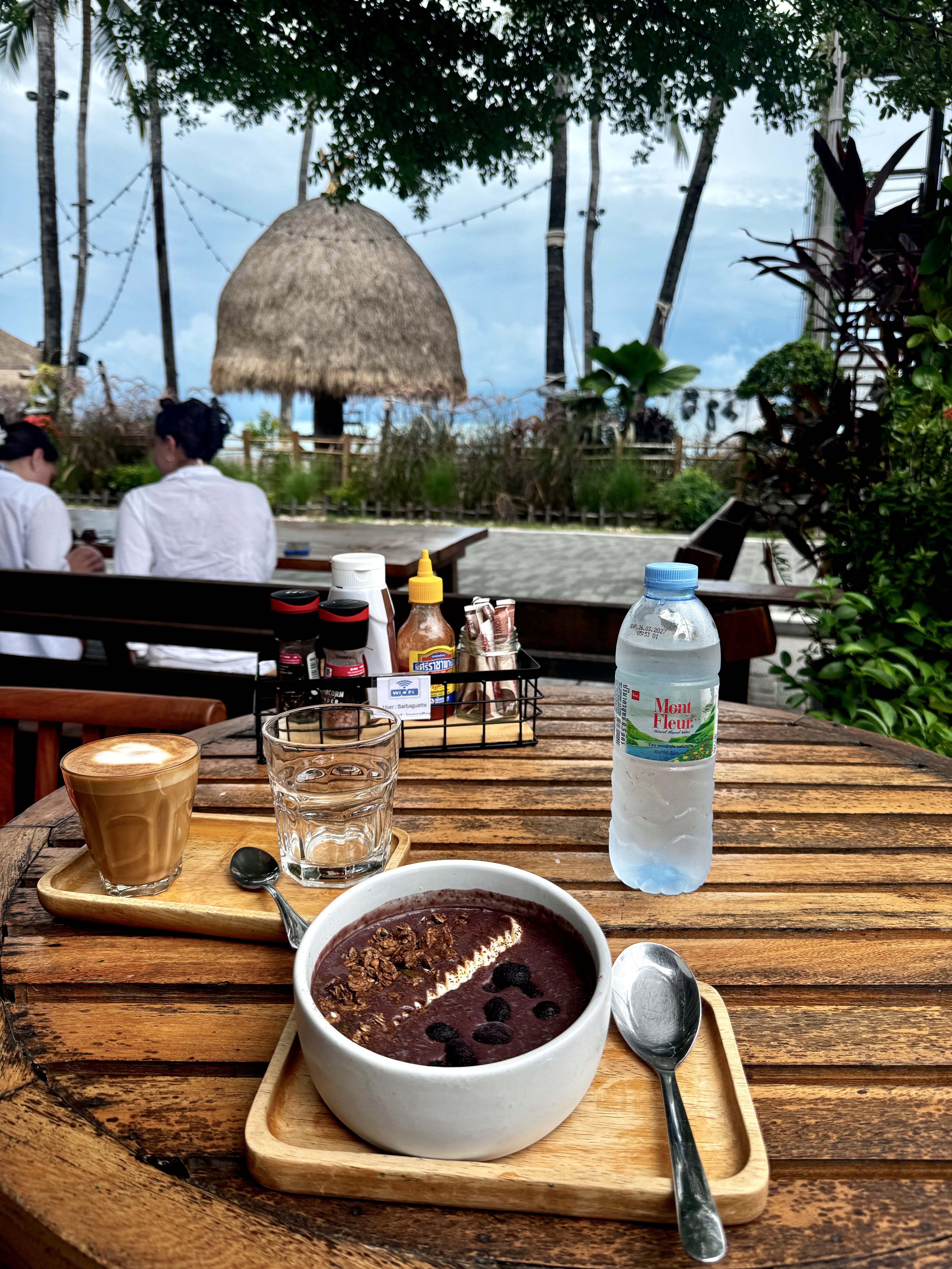 A bowl of acai is placed on a table at a café with views of the ocean in Koh Samui, Thailand.