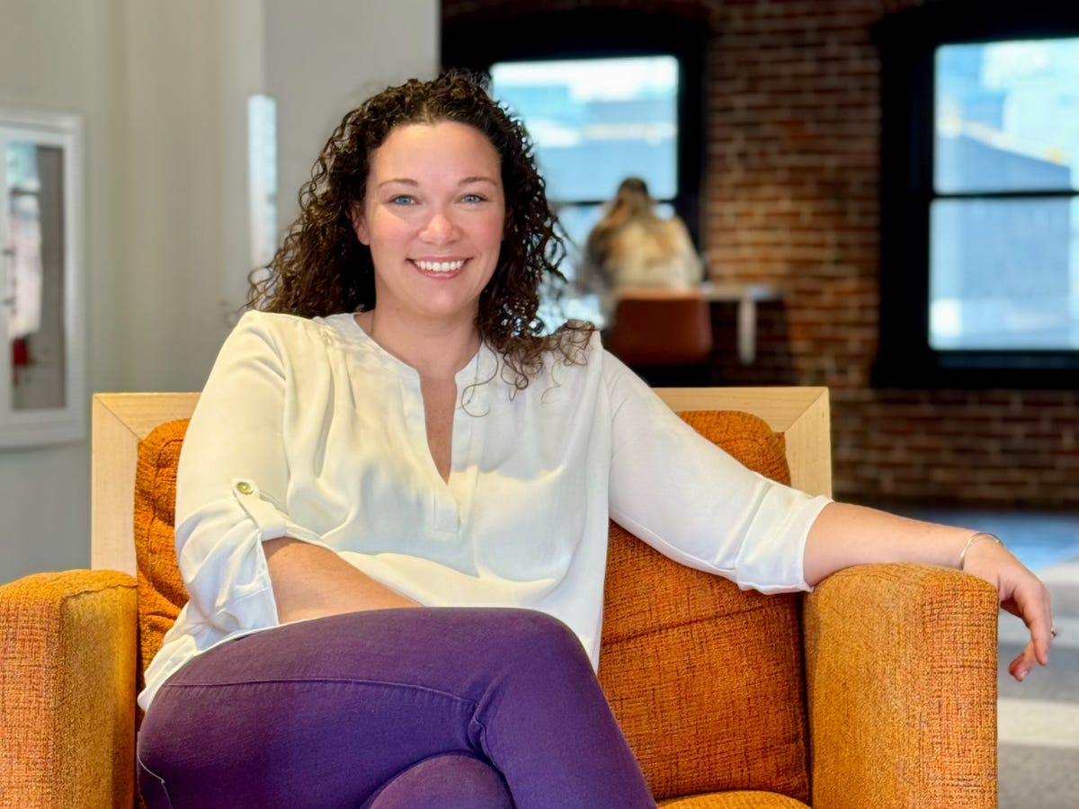 Grace Cleveland sits in an orange chair and smiles at the camera