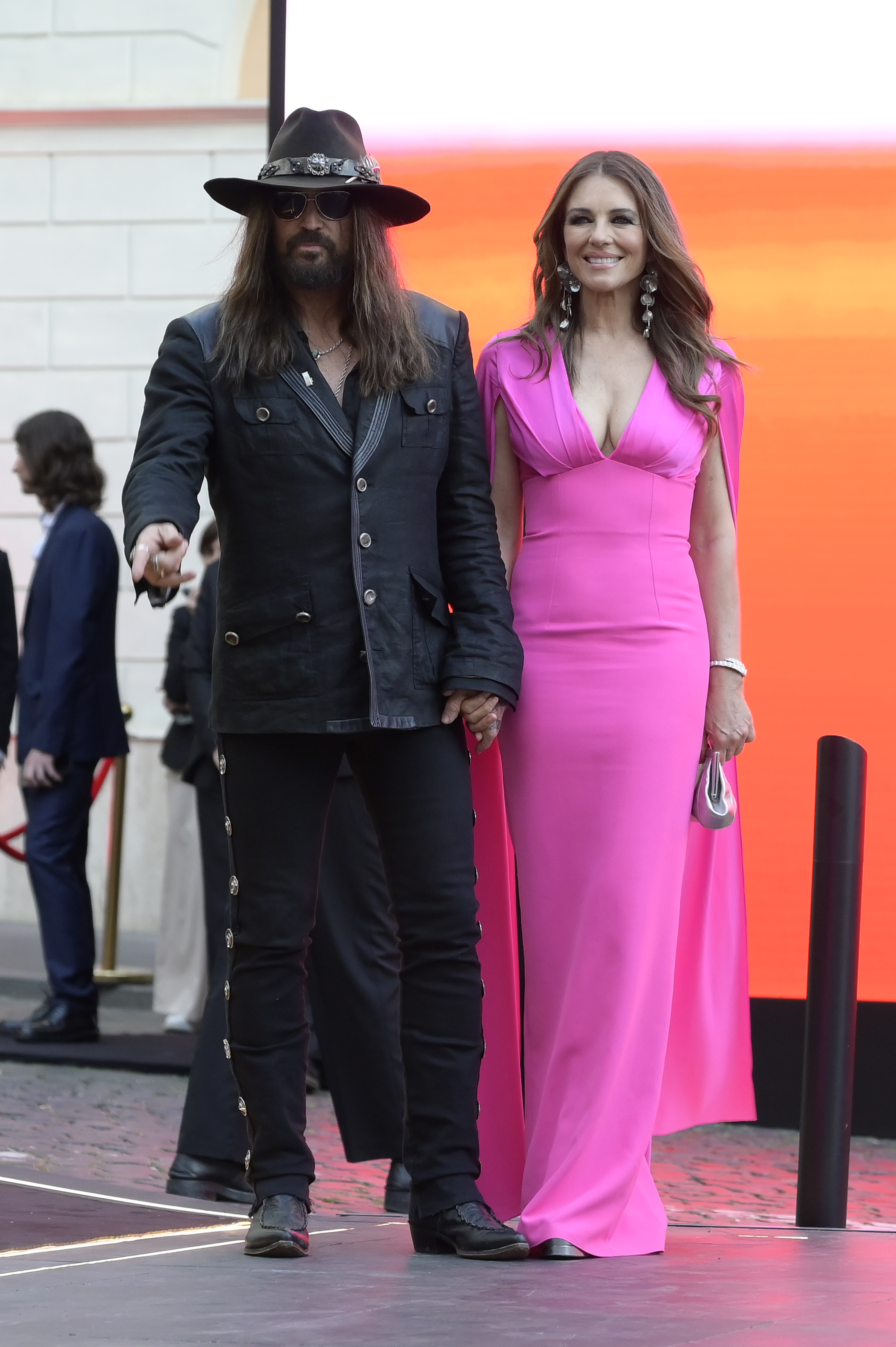 Billy Ray Cyrus and Elizabeth Hurley holding hands in Rome