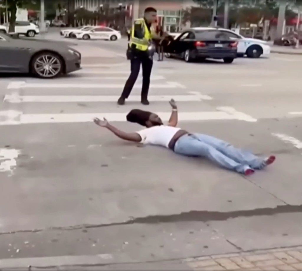 The driver then bolts from the BMW in a blood-stained white shirt but stops a few feet away before he’s ordered by the officer who shot him to get on the ground in the middle of the street.