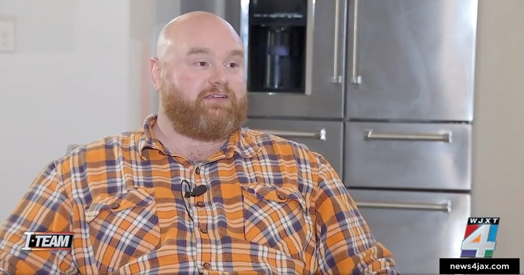 Bradley Byrd sits in his kitchen in front of his new refrigerator after the costly flood.
