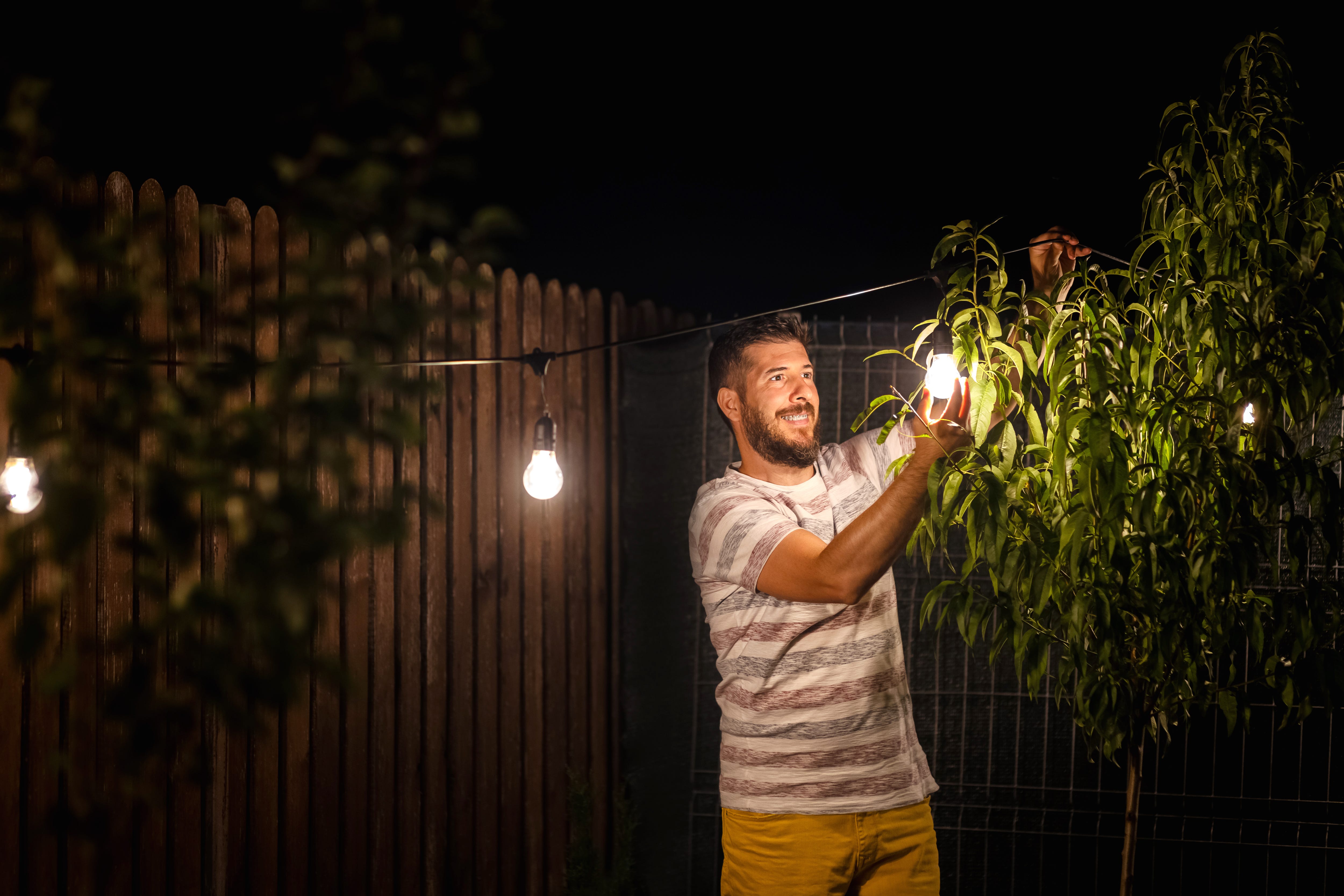 man setting up lights in the backyard