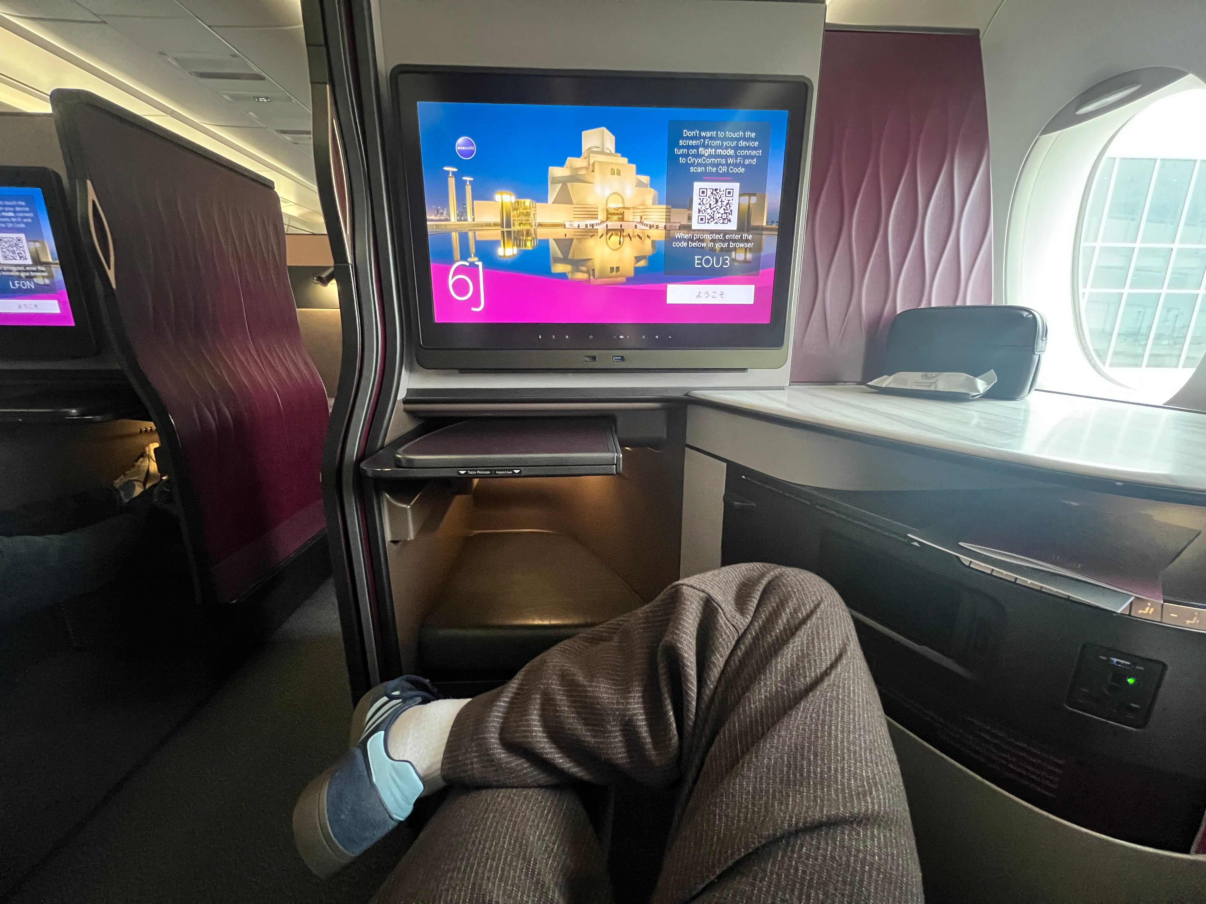 A first-person perspective sat in a Qatar Airways QSuite business class seat.