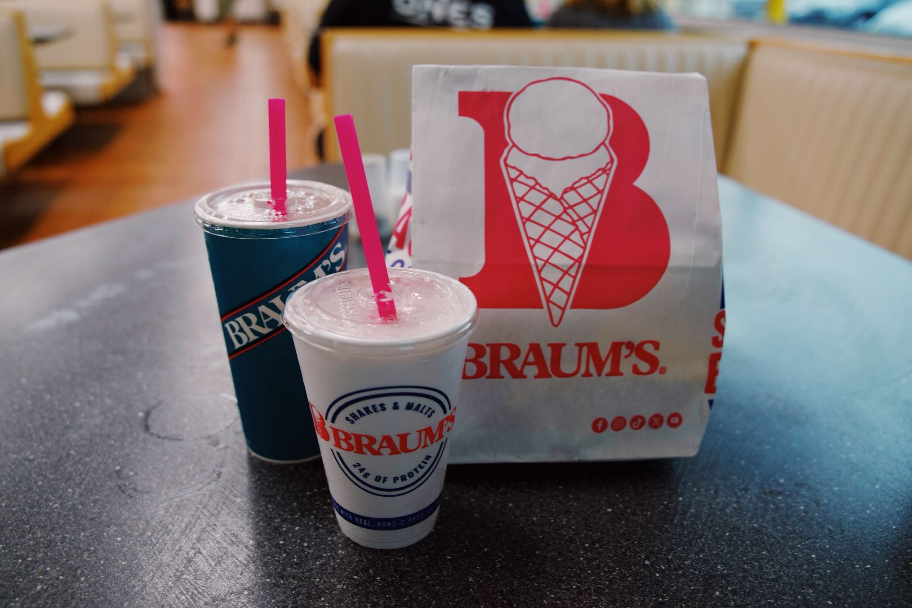 A Braum's togo bag next to a sweet tea and malt drink.