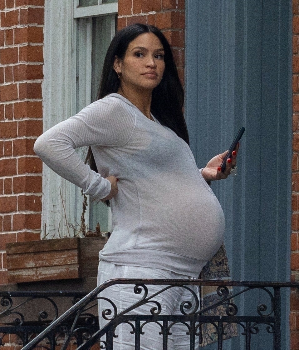 A pregnant Cassie holding her phone