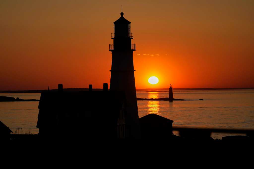 The sun rises beyond the lighthouses of Portland Head, foreground, and Ram Island Ledge, Wednesday, May 28, 2025, in Cape Elizabeth, Maine. 