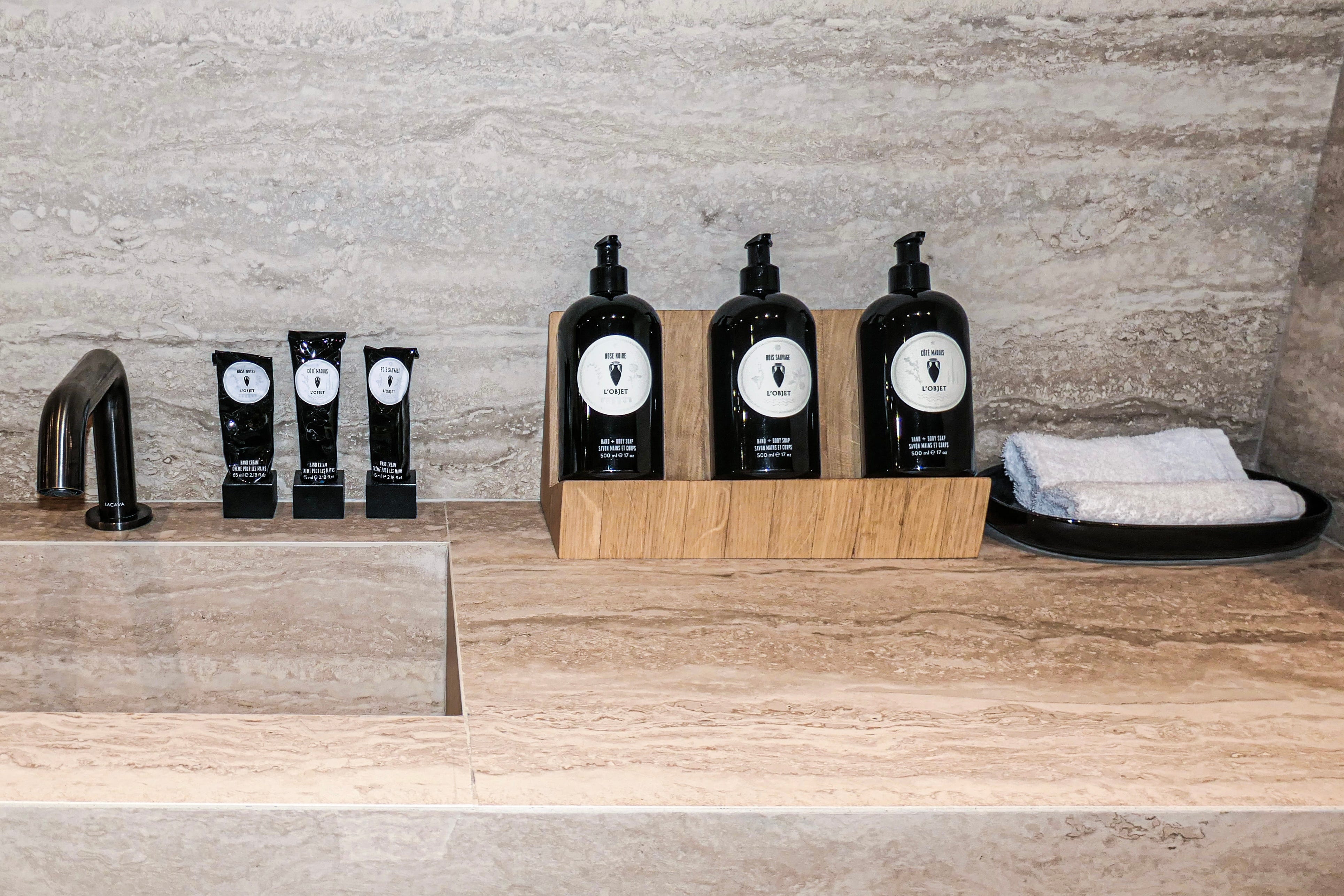 L'Objet hand and body soap samples and bottles lined up near a sink
