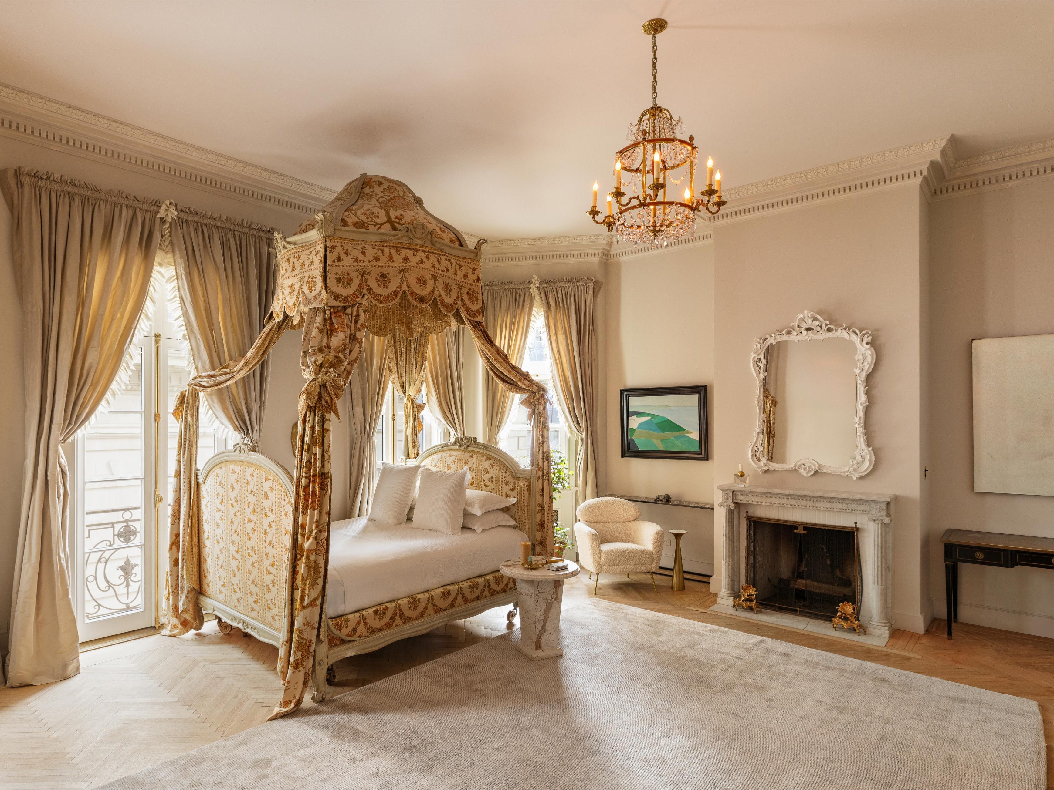 a bedroom with a canopy bed, chandelier, and marble fireplace