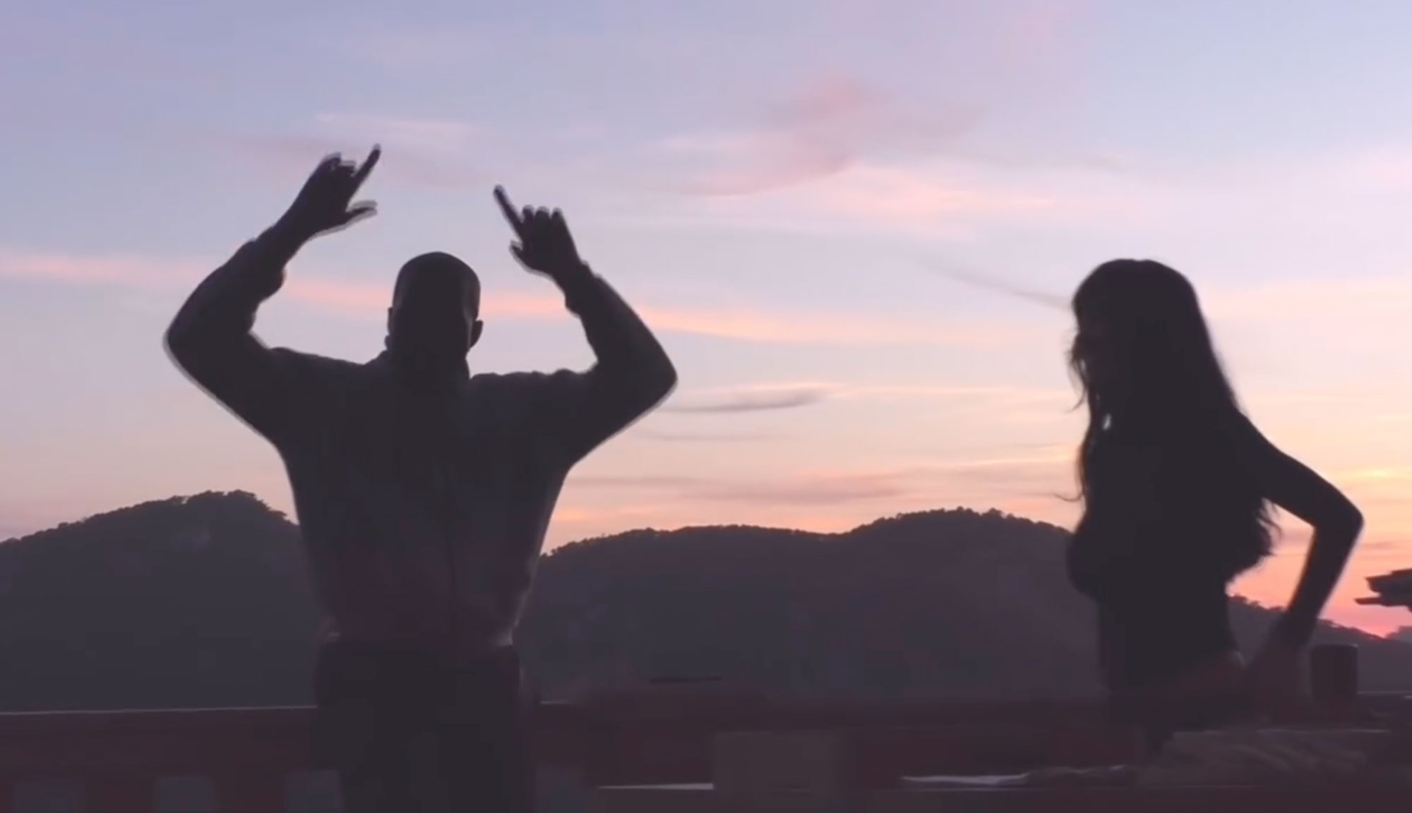 Kanye West raises his arms with Bianca Censori at sunset. 