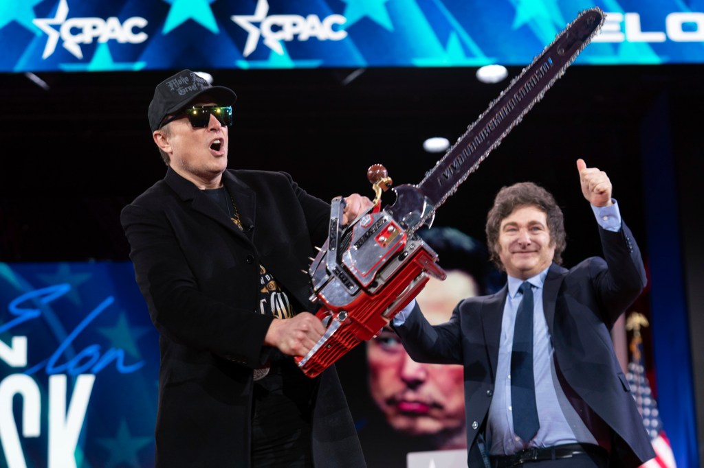Musk holds up a chainsaw he received from Argentina's President Javier Milei, right, as they arrive to speak at the Conservative Political Action Conference, CPAC, at the Gaylord National Resort & Convention Center, Feb. 20, 2025, in Oxon Hill, Md.