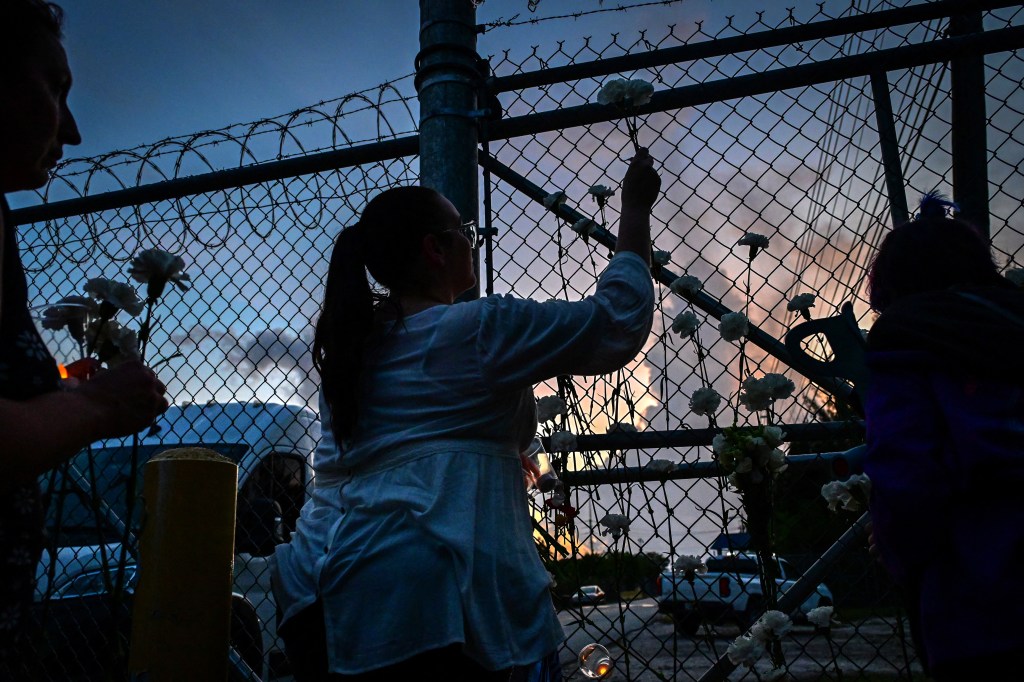 People place white carnation flowers on the fence of the Krome Detention Center during a vigil protesting US Immigration and Customs Enforcement custody and mass deportations in Miami on May 24, 2025. 