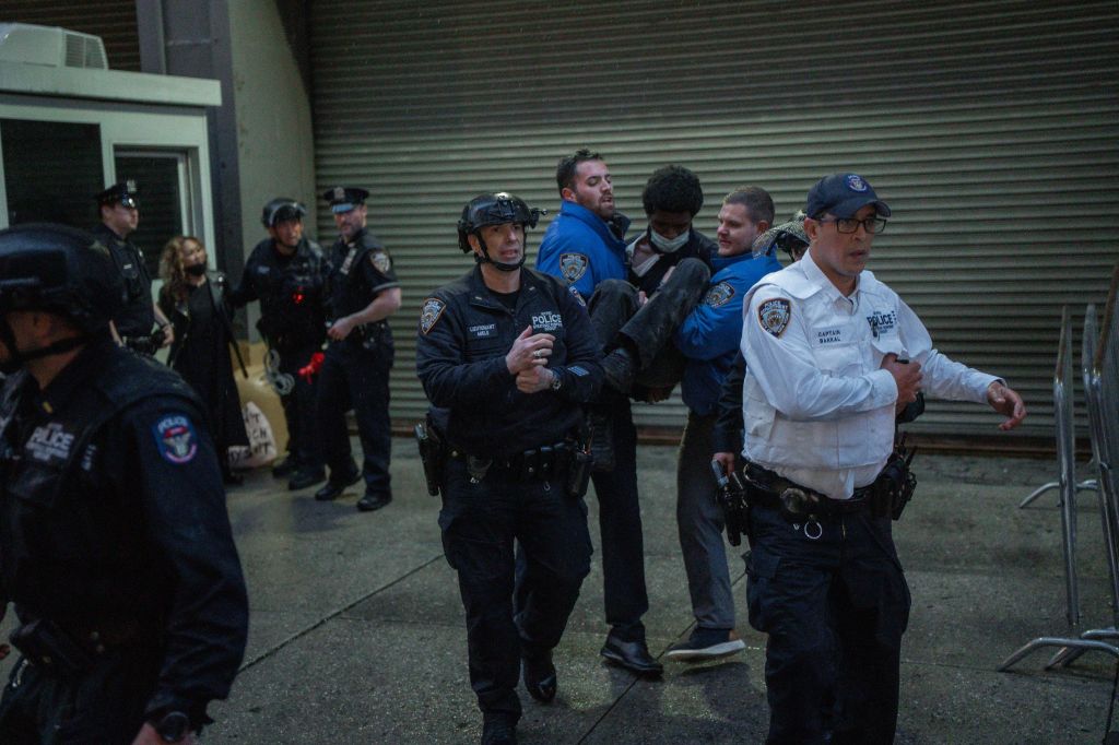 Protester being carried by police officers after arrest at immigration demonstration outside the Varick Street ICE facility in Manhattan, New York, USA