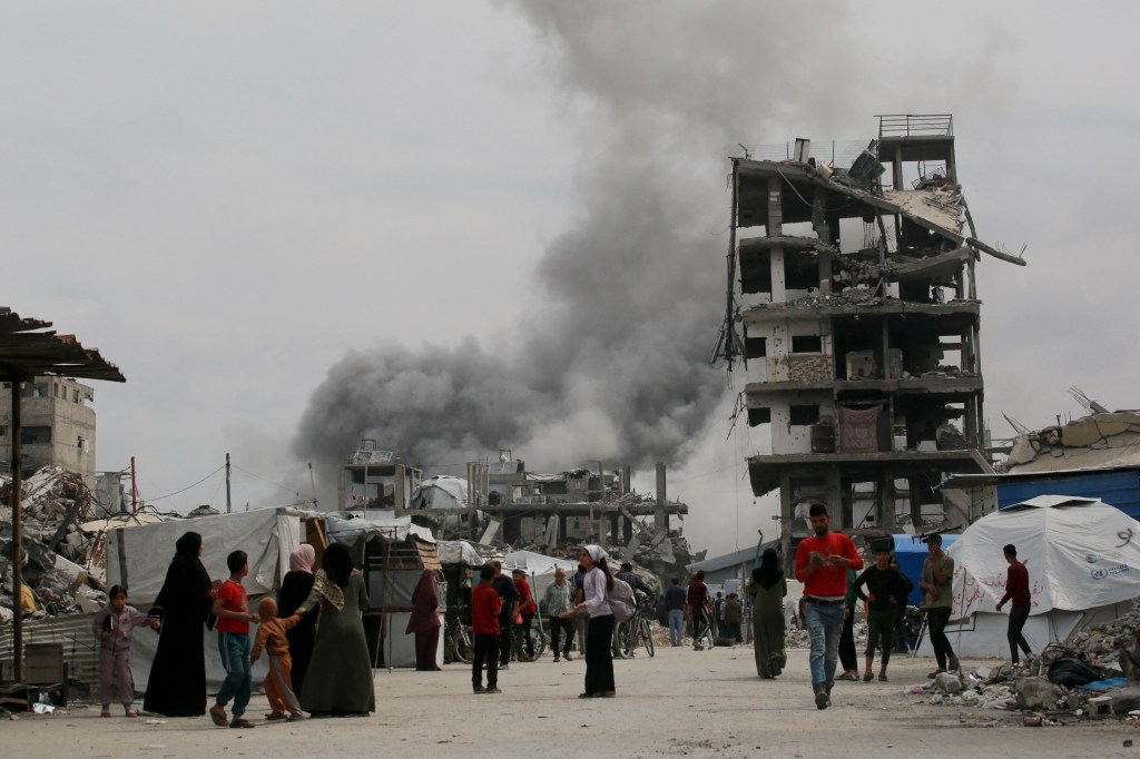 Palestinians run for cover as an Israeli strike hits the home (L) of the Hmeid family in Jabalia in the northern Gaza Strip on May 15, 2025. 