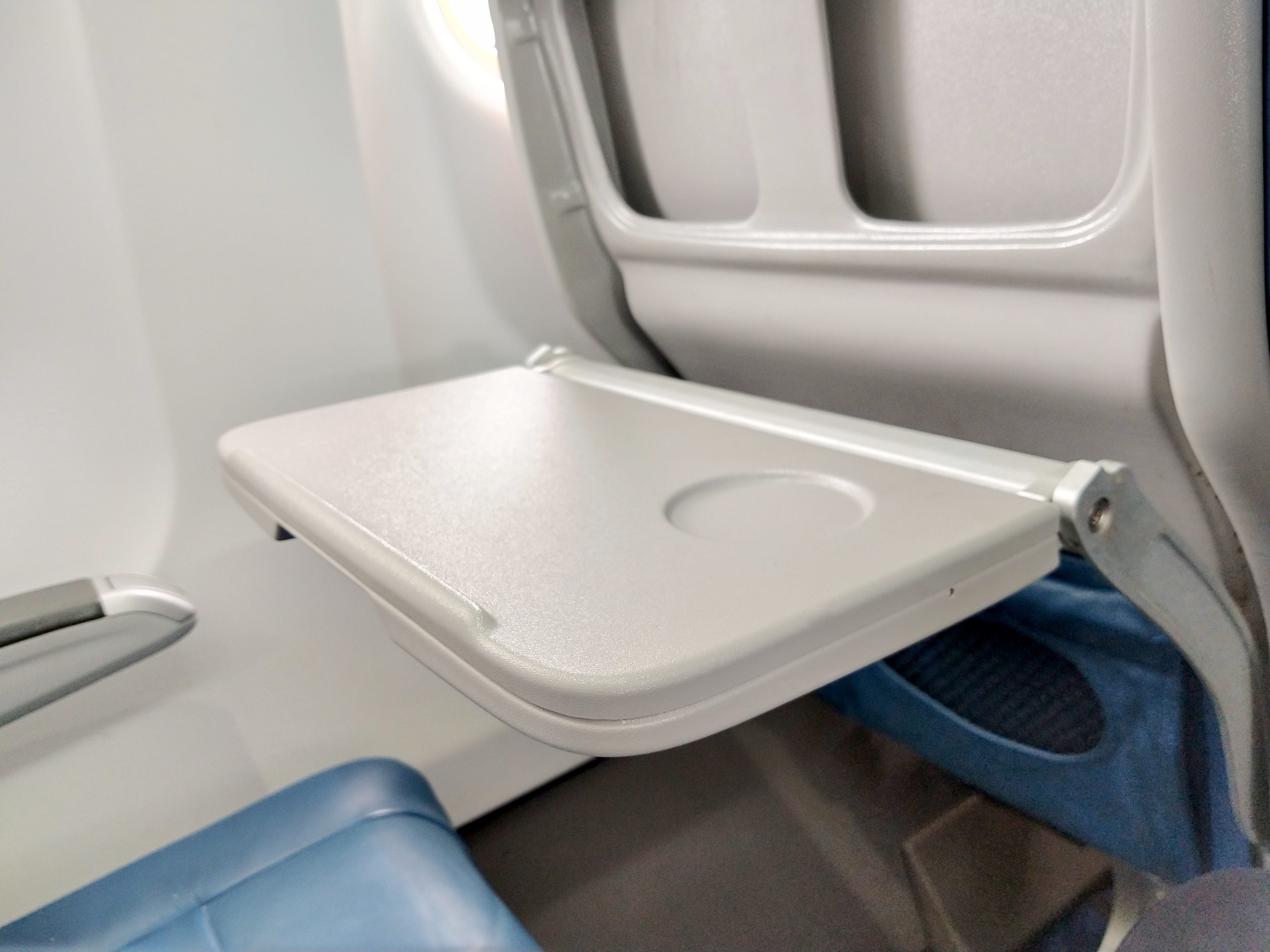 A gray tray in front of an aircraft seat.