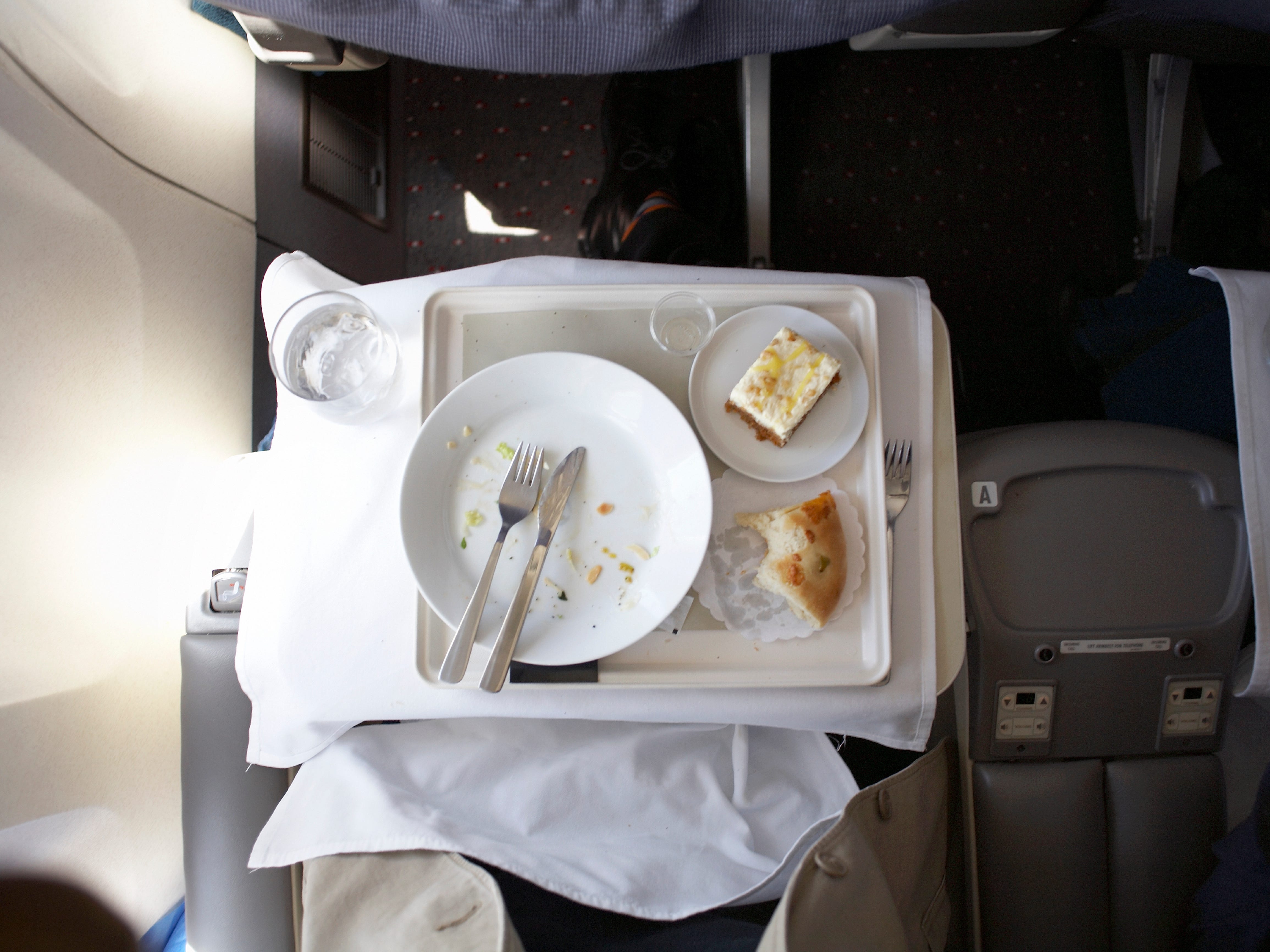 An empty plate that food has been eaten off of, along with cutlery and dessert.
