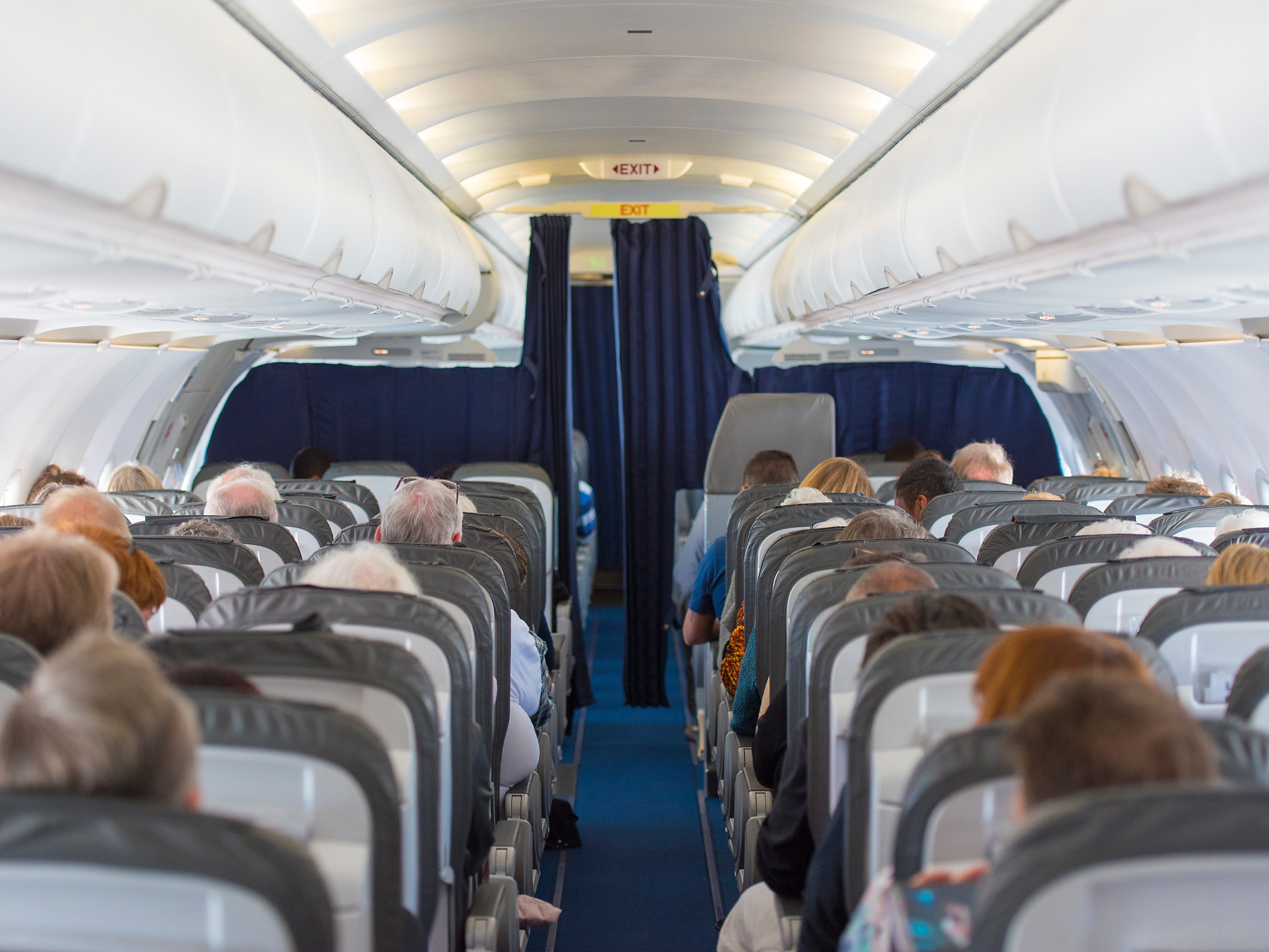 Commercial aircraft cabin filled with passengers in its seats.